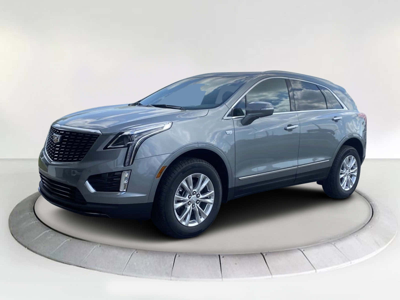 Cadillac Xt5 桌布 壁紙 — 一輛時尚的灰色凱迪拉克SUV在純白色工作室背景的襯托下，展示在圓形石台上。