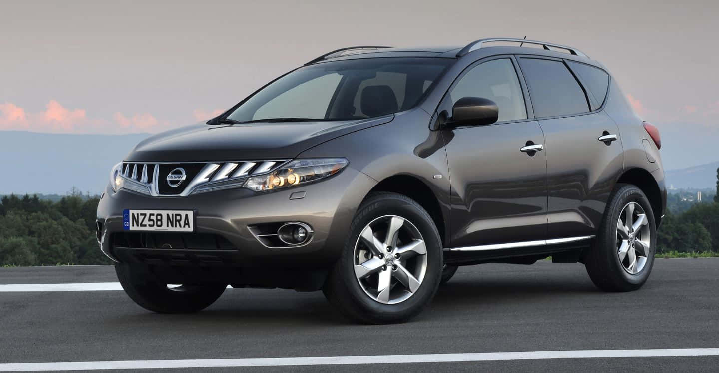 Nissan Murano 桌布 壁紙 — 一輛時尚的灰色日產Murano SUV停在柏油路上，遠處是樹木成行的地平線，天空柔和暮色。