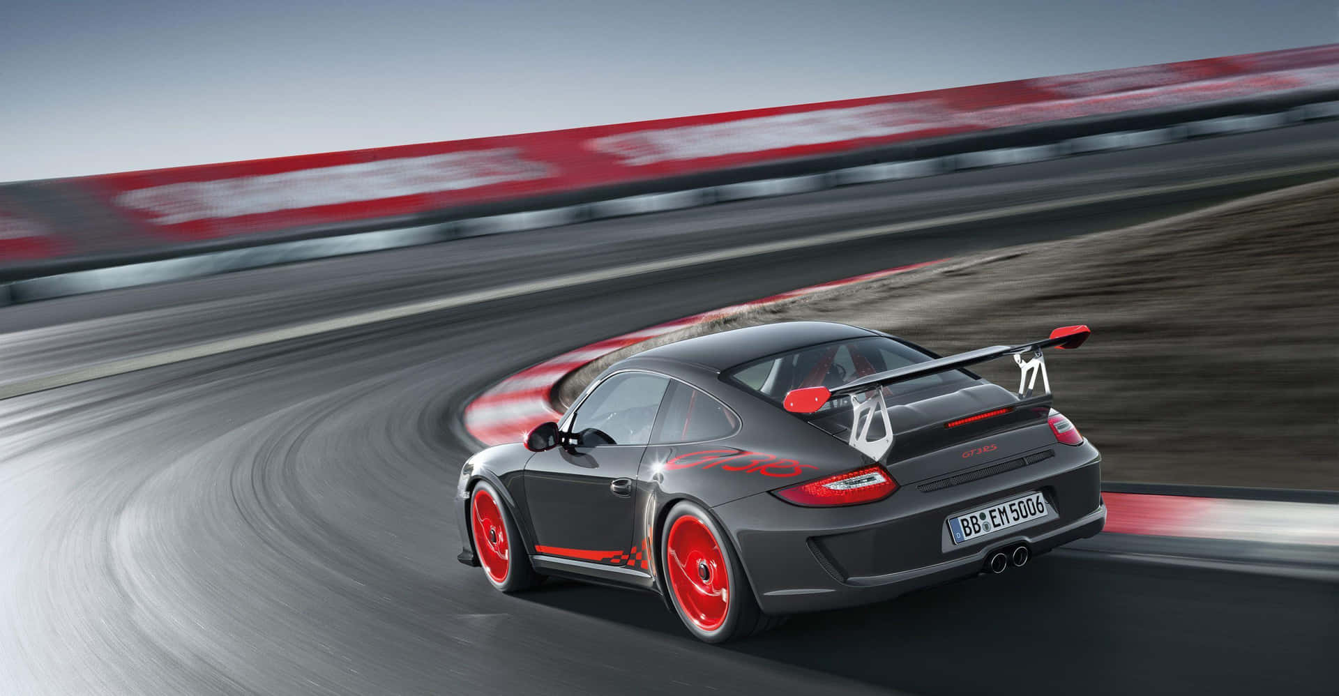  壁紙 — 一輛流線型灰色保時捷911 GT3 RS帶紅色點綴，在彎曲賽道上以動態模糊效果奔馳。