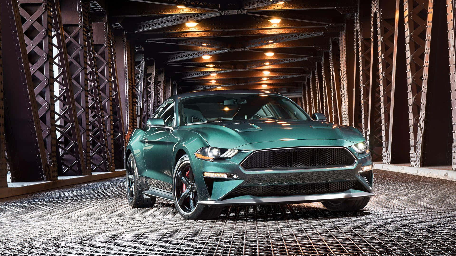 Ford Mustang Bullitt 桌布 壁紙 — 一輛時尚的綠色福特野馬停泊在鋼橋下，溫暖的頭頂燈光在其光滑表面反射。