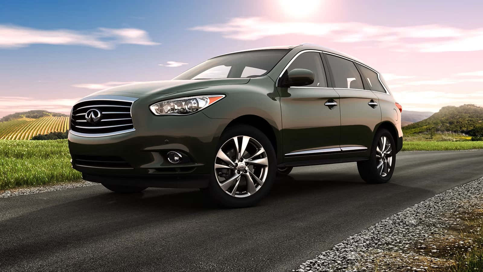 Infiniti Qx60 桌布 壁紙 — 一輛時尚的綠色Infiniti SUV在日落時分沿著蜿蜒的道路穿過起伏的葡萄園山丘行駛。