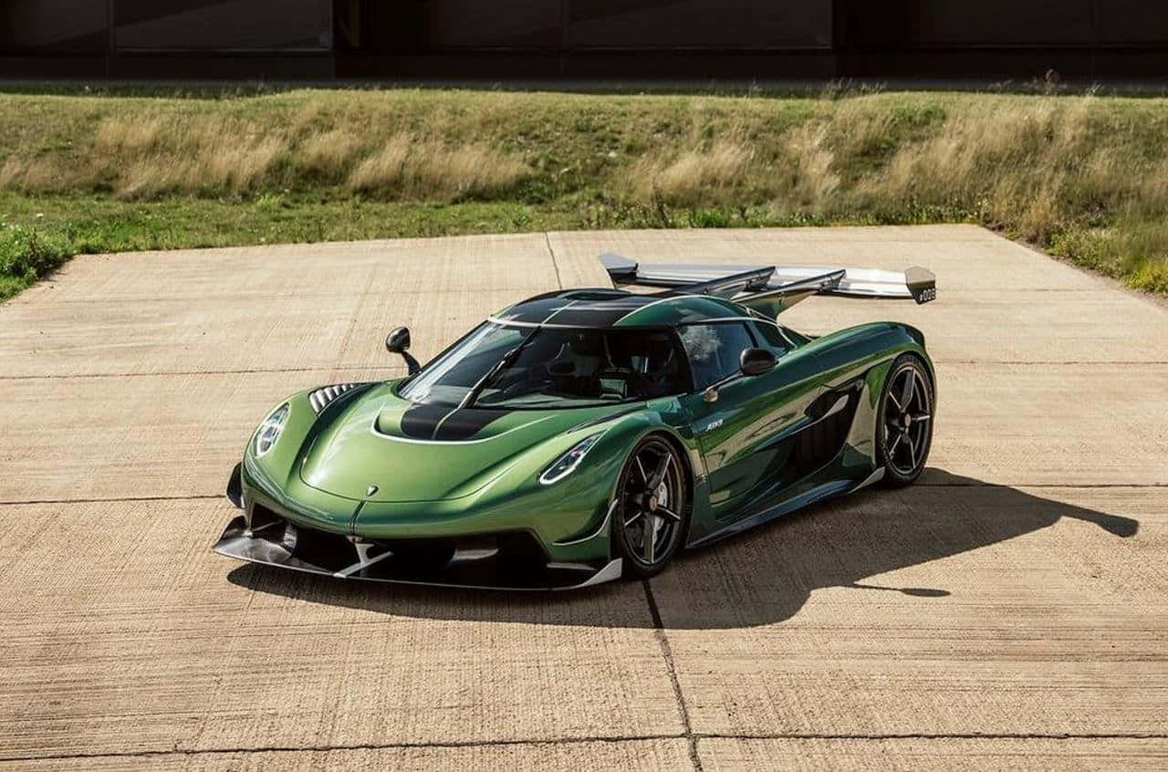  壁紙 — 一輛時尚的綠色Koenigsegg hypercar，帶有大型後擾流板，在明亮的日光下停放在混凝土表面上。