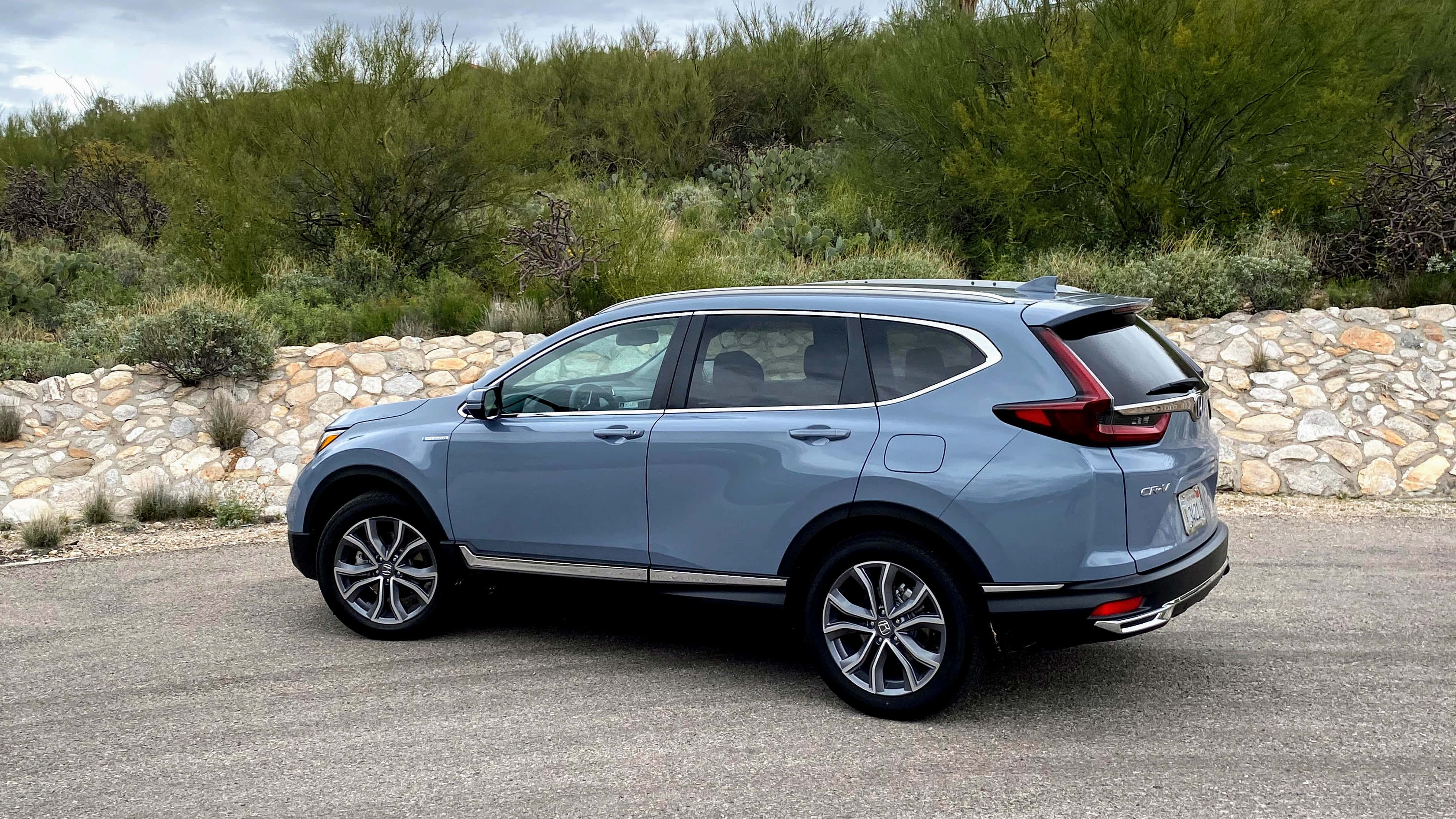 Honda Cr-v 桌布 壁紙 — 一輛時尚的淺藍色本田CR-V SUV停在柏油路上，旁邊是石牆和綠色灌木叢。
