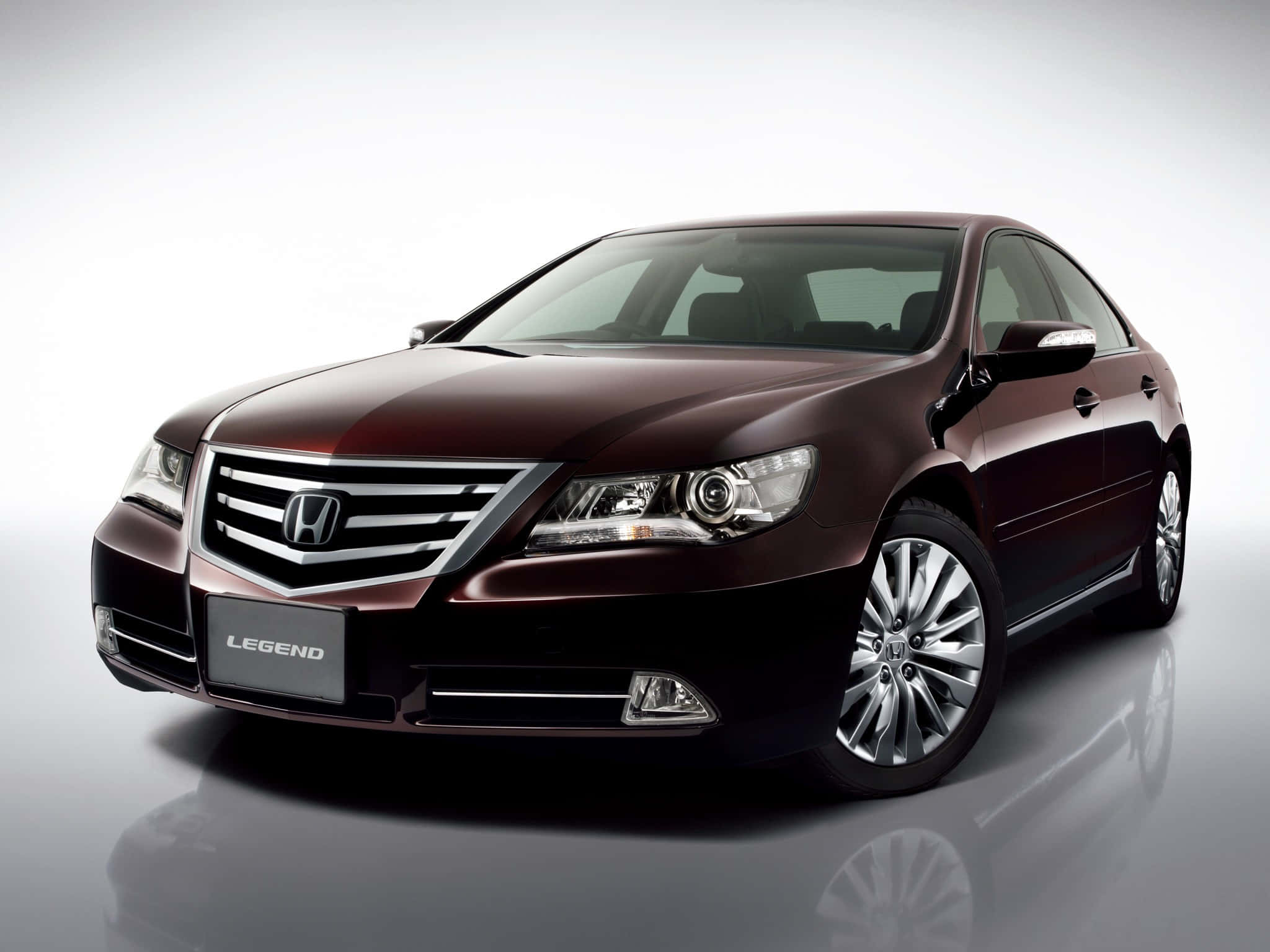 Honda Legend 桌布 壁紙 — 一輛時尚的栗色本田Legend轎車在攝影棚燈光下，在反光的灰色地板上閃閃發光。