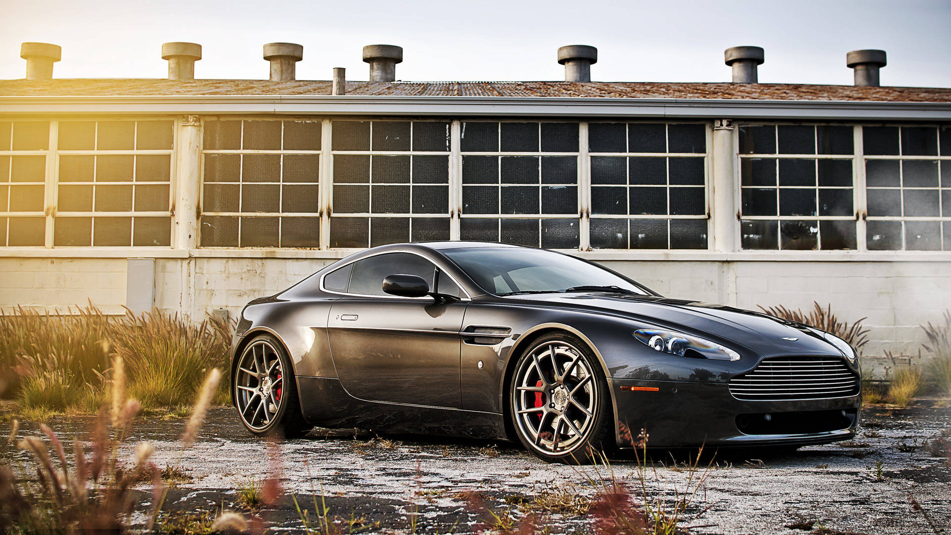 消光黑色Aston Martin停放在舊工業建築前，夕陽時分。 — 汽車 4K 壁紙