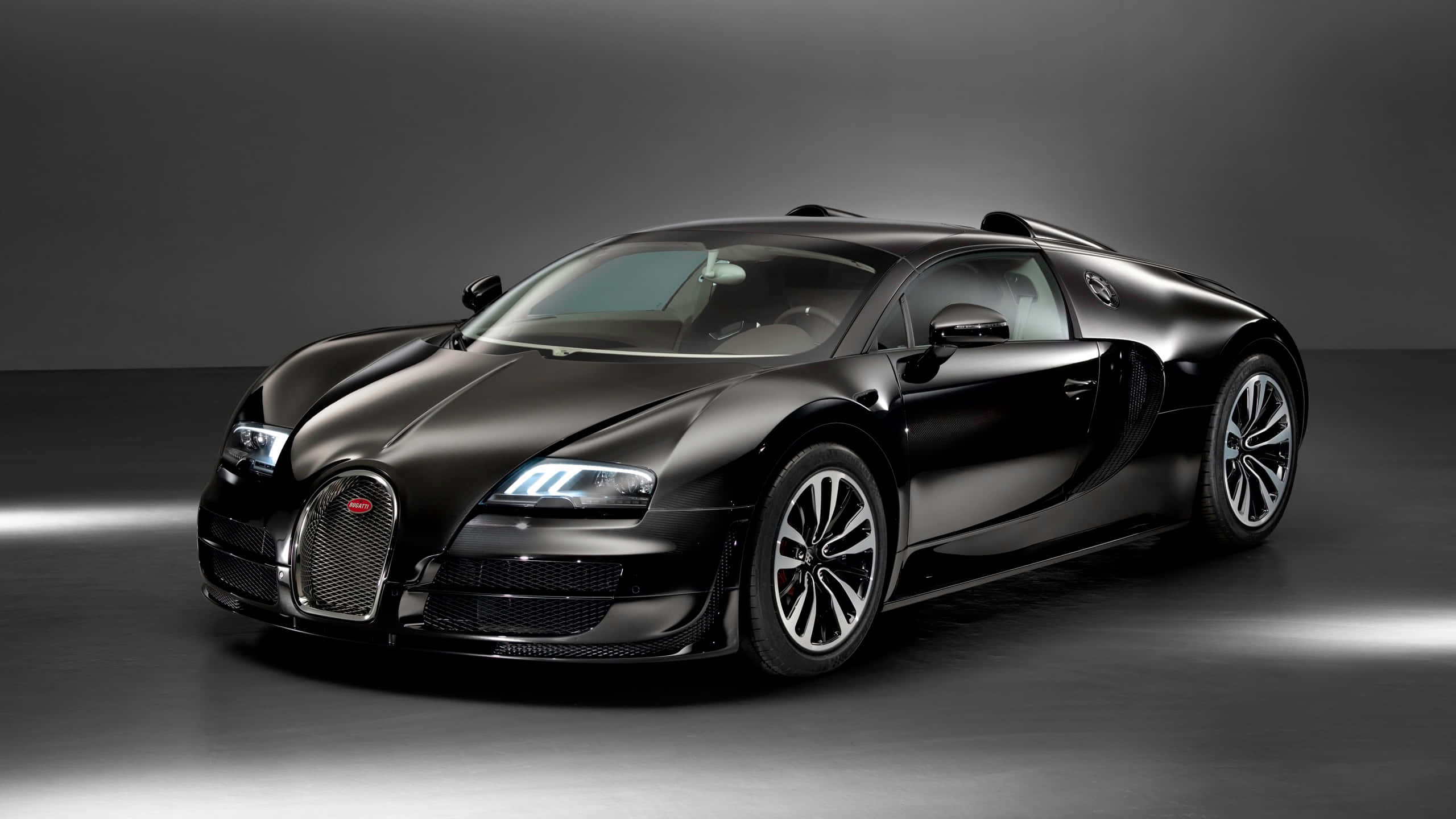 Bugatti Veyron 桌布 壁紙 — 一輛時尚的消光黑色Bugatti Veyron跑車在深灰色背景前的攝影棚燈光下閃耀。