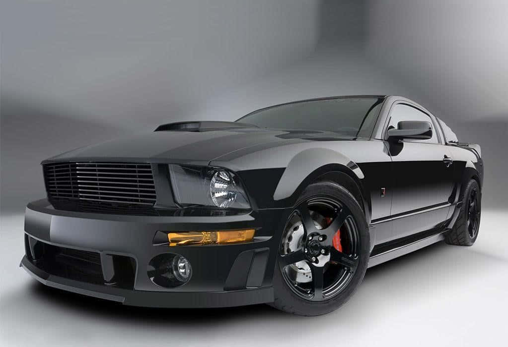 Ford Mustang Roush 桌布 壁紙 — 一輛光滑的啞光黑色福特野馬跑車，配備紅色制動卡鉗和光澤輪轂，在工作室環境中擺拍。
