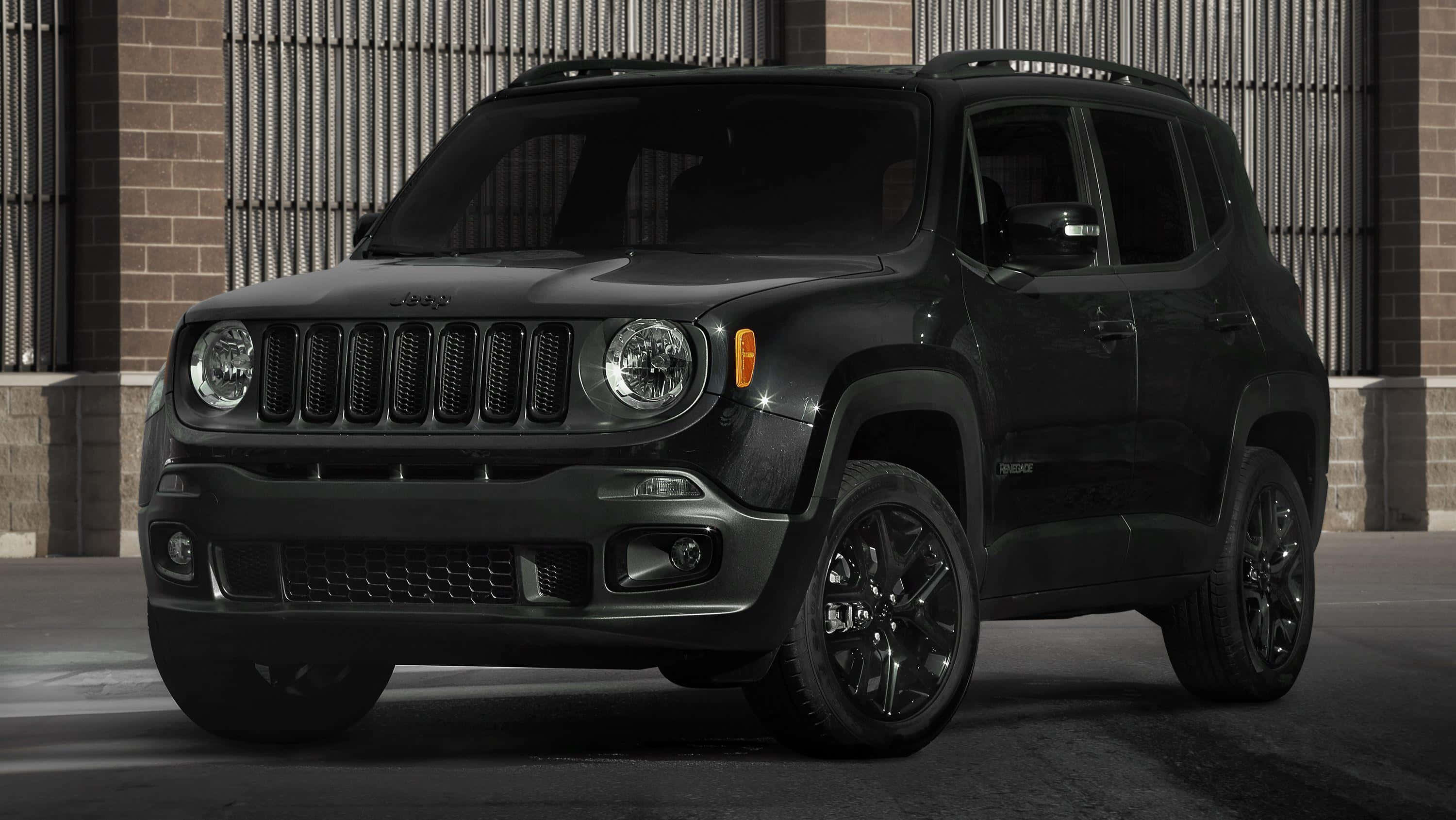 Jeep Renegade 桌布 壁紙 — 一輛時尚的消光黑色Jeep Renegade SUV停在一棟帶金屬格柵的磚造建築前。