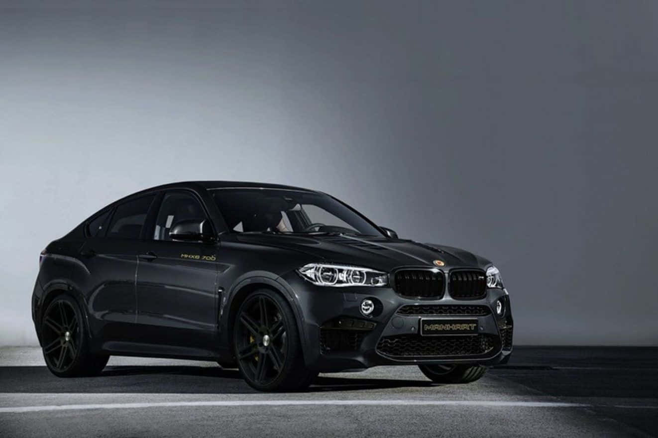 Bmw X6 桌布 壁紙 — 一輛光滑的啞光黑色Mansory改裝BMW X6 M停在簡約的攝影棚地板上，配以戲劇性的燈光。