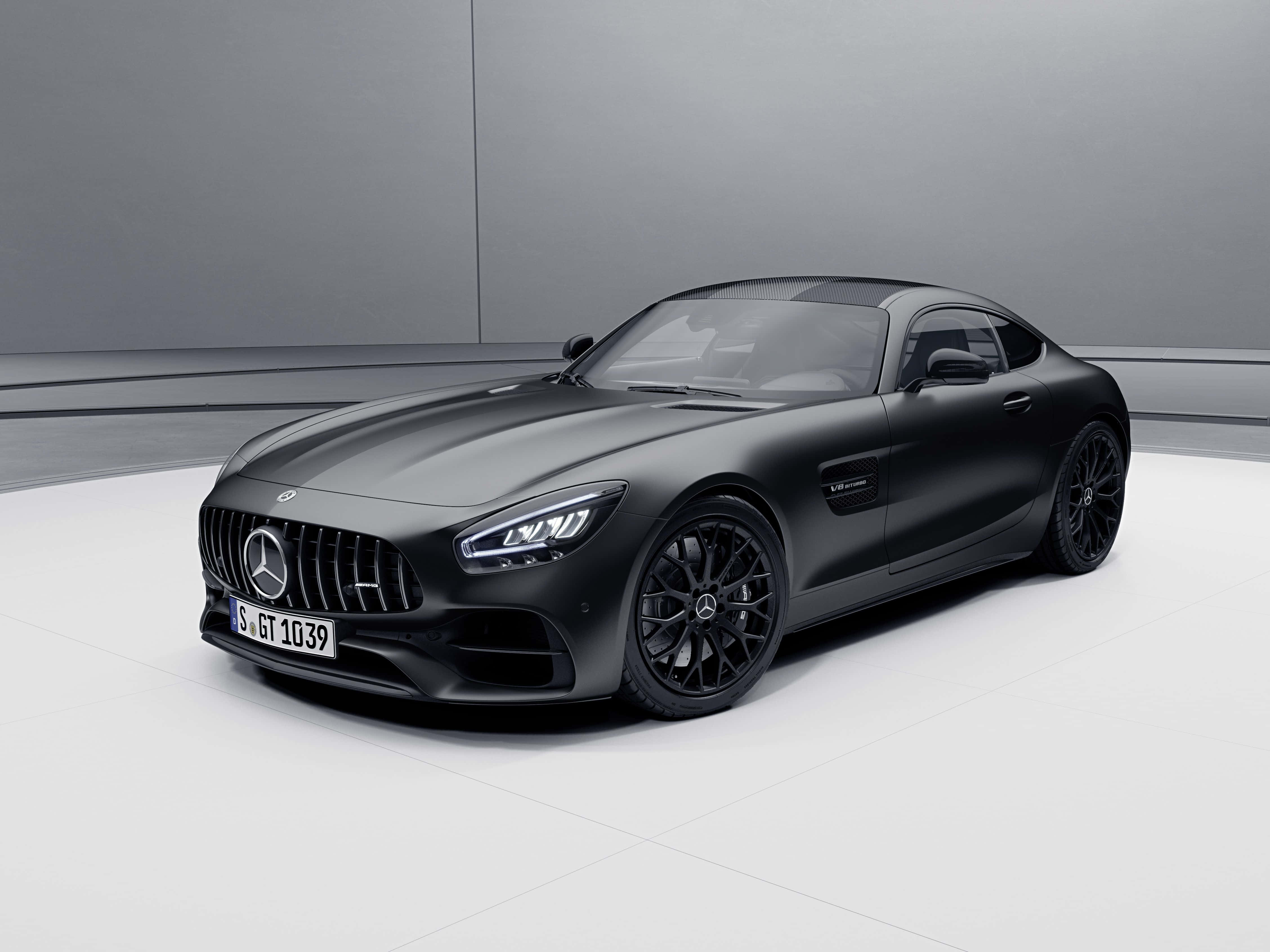 Mercedes Benz Amg Gt 桌布 壁紙 — 一輛時尚的啞光黑色梅賽德斯-AMG GT跑車在簡約的工作室中展示，配有潔白的白色地板和灰色牆壁。