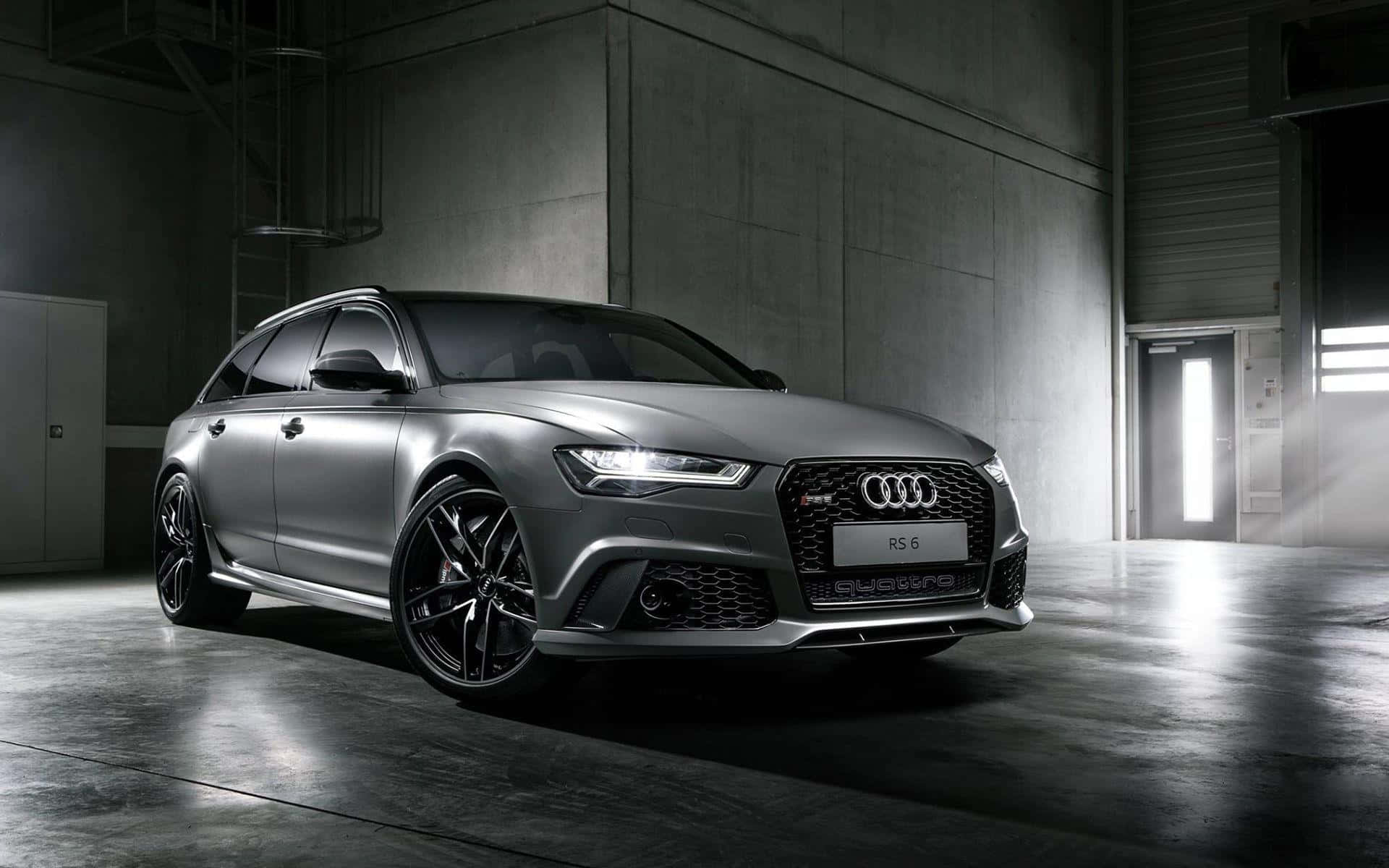 Audi Rs6 桌布 壁紙 — 一輛時尚的消光灰色奧迪RS6 Avant旅行車在簡約工業倉庫中，混凝土牆壁和地板，燈光效果極具戲劇性。