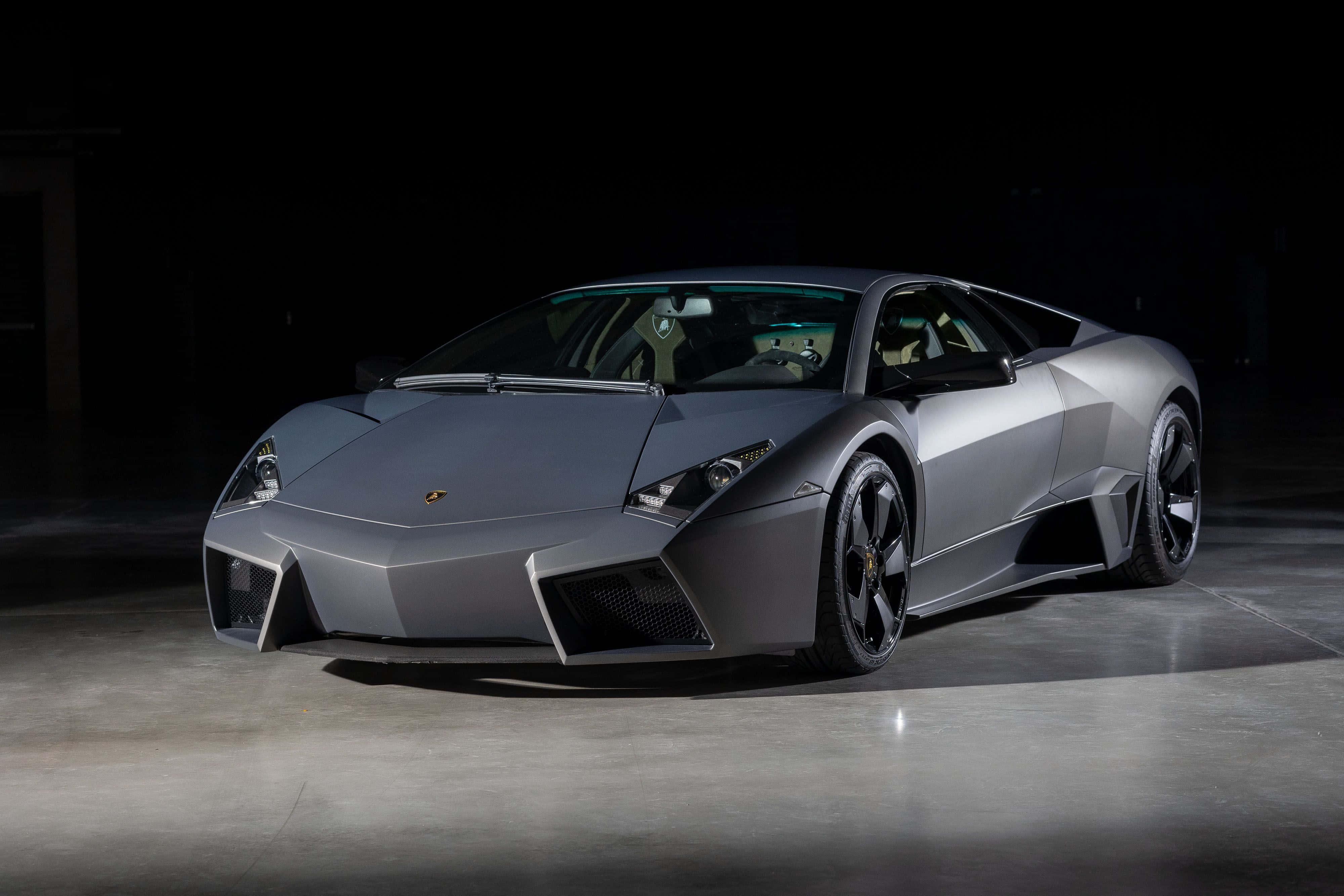 Lamborghini Reventón 桌布 壁紙 — 一輛時尚的啞光灰色藍寶堅尼Reventon跑車在黑暗的攝影棚背景下被戲劇性地照亮。