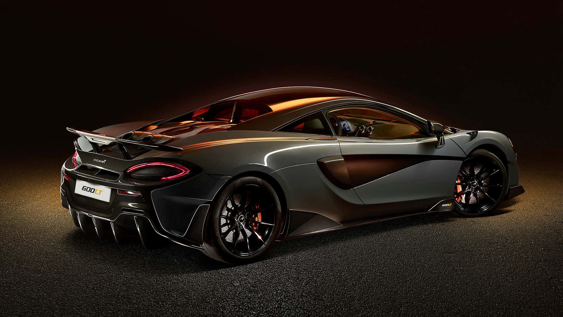 Mclaren 600lt 桌布 壁紙 — 一輛時尚的啞光灰色McLaren 600LT跑車在戲劇性的工作室燈光下，在深色背景中閃耀。
