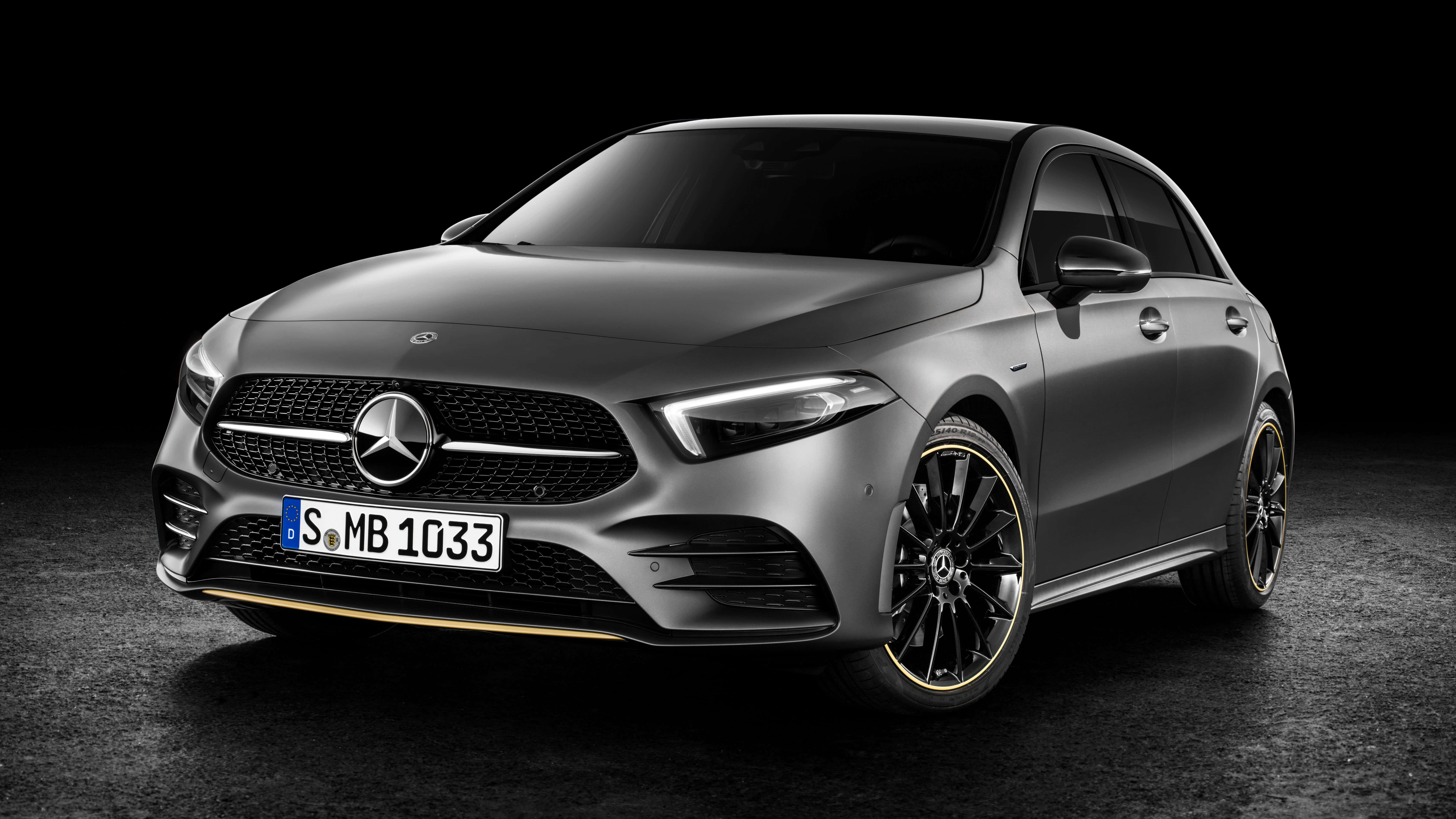 Mercedes Benz A-class 桌布 壁紙 — 一輛時尚的消光灰色梅賽德斯-奔馳A級轎車，配備黑色輪圈和金色飾邊，在黑暗的攝影棚背景下展示。