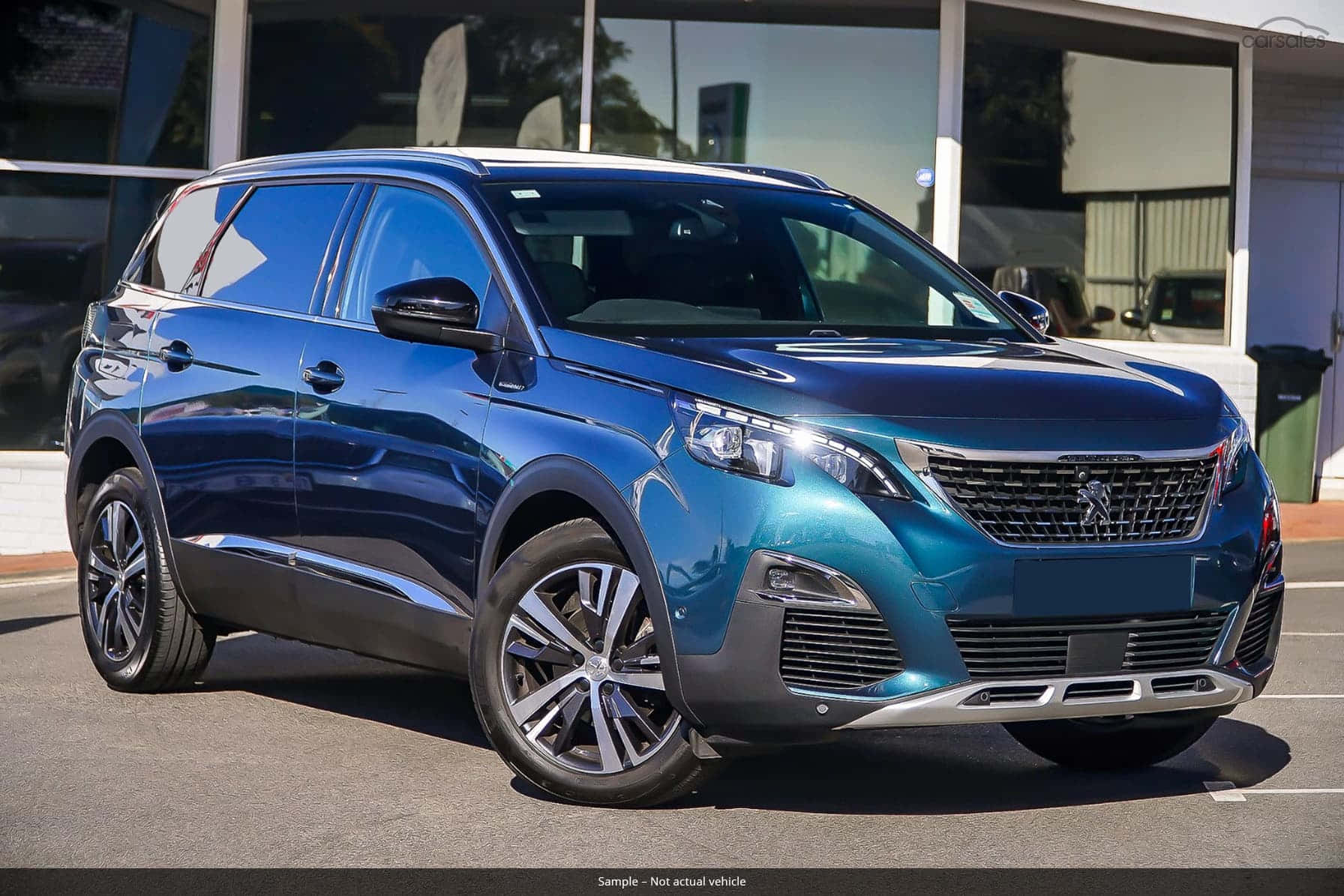 Peugeot 5008 桌布 壁紙 — 一輛時尚的金屬藍色標緻SUV在明亮的日光下停放在現代玻璃建築外。