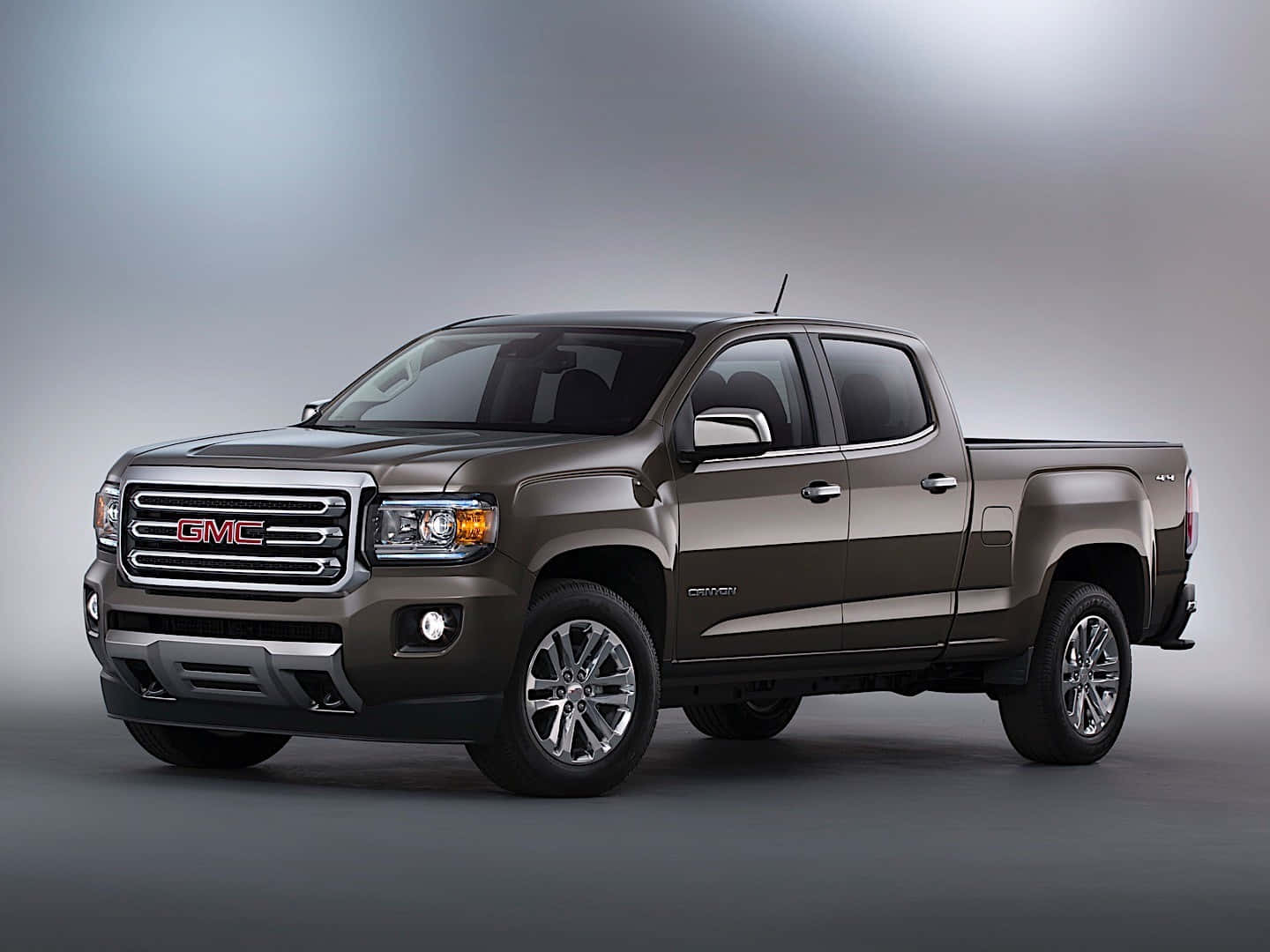 Gmc Canyon 桌布 壁紙 — 一輛時尚金屬棕色GMC Canyon皮卡車在專業工作室環境中展示，配有柔和漸變燈光。