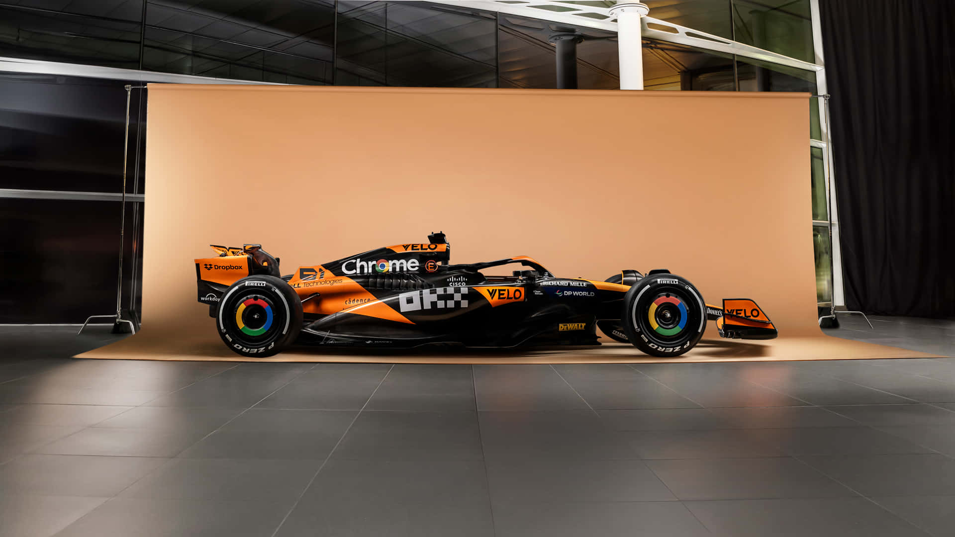 一輛帶有橙色和黑色塗裝的一級方程式賽車在工作室中展示。 — F1 壁紙