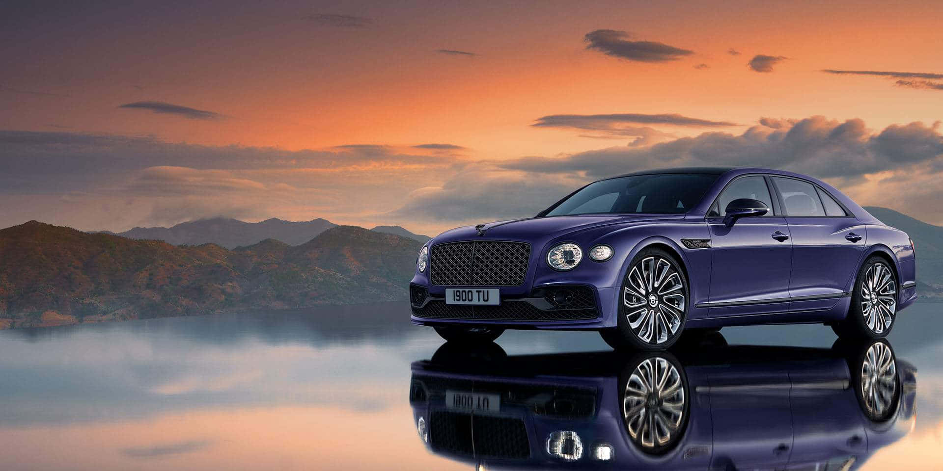 Bentley Mulsanne 桌布 壁紙 — 一輛時尚的紫色賓利轎車完美地倒映在平靜的水面上，背景是充滿活力的橙色日落天空和遠處的山脈。