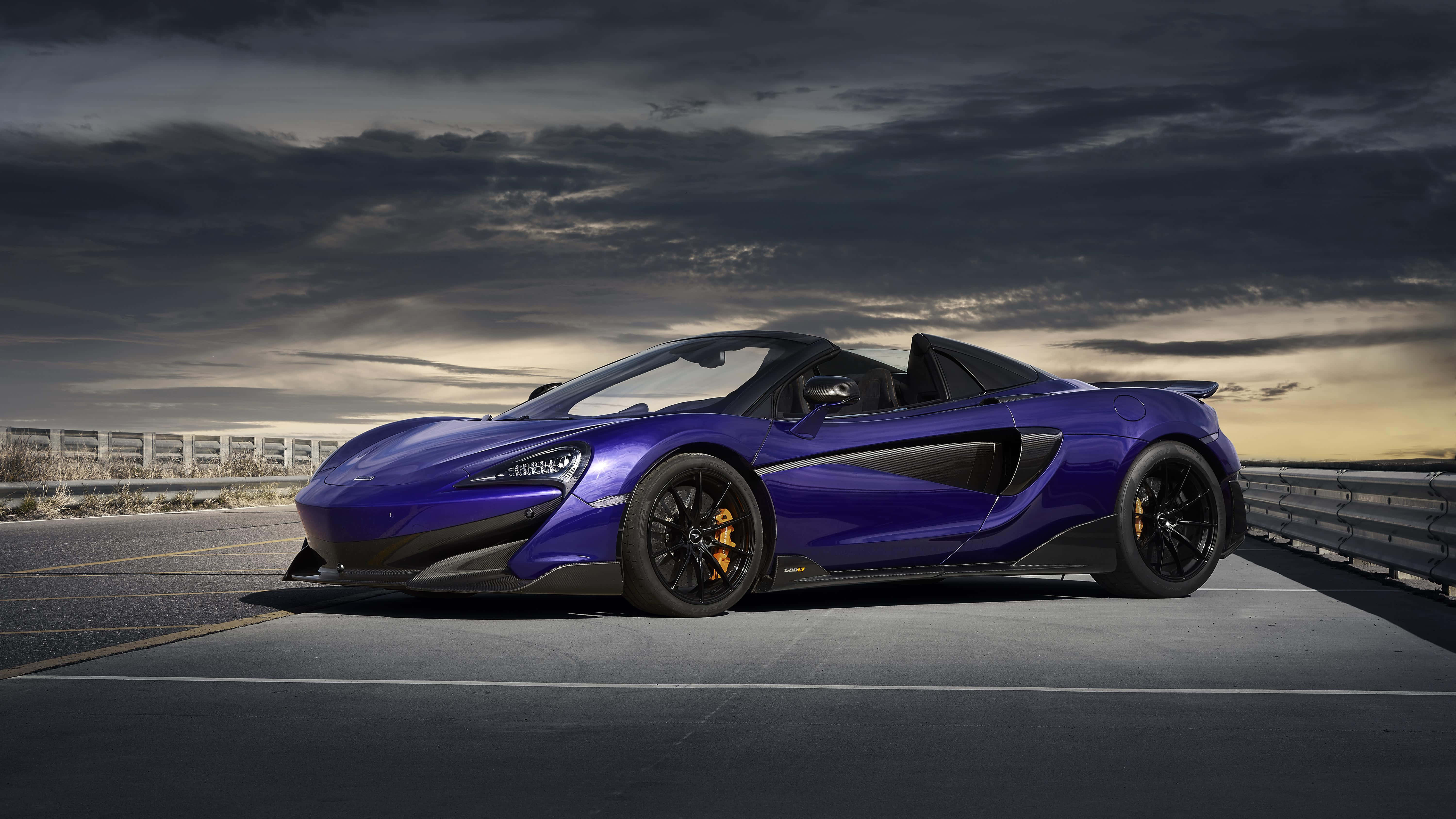 Mclaren 600lt 桌布 壁紙 — 一架時尚的紫色McLaren 570S Spider敞篷跑車在黃昏時停泊在高速公路上，天空佈滿戲劇性的雲層。