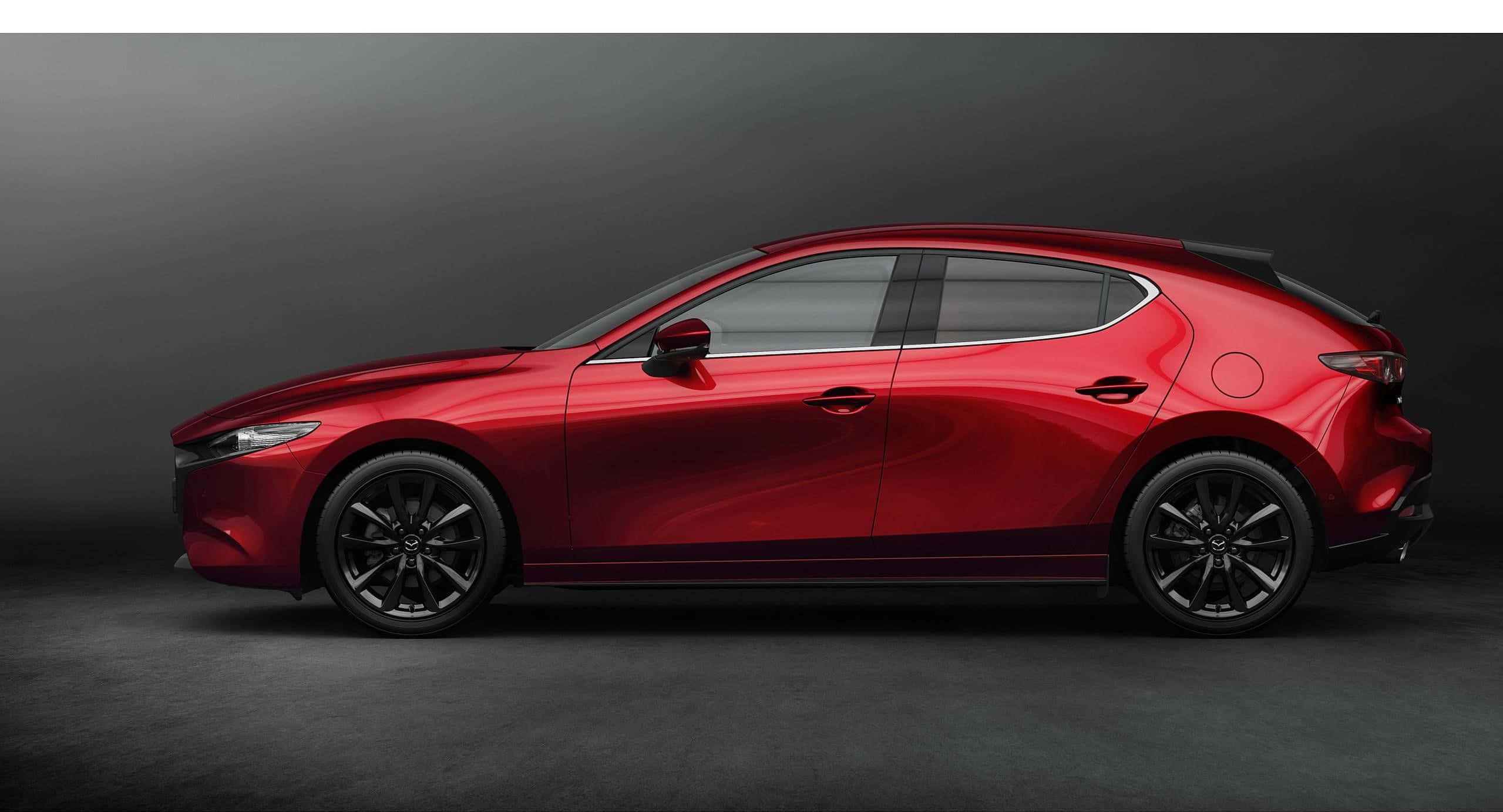 Mazda 3 Hatchback 桌布 壁紙 — 一輛時尚的紅色Mazda 3掀背車在深灰色背景的攝影棚燈光下閃閃發光。