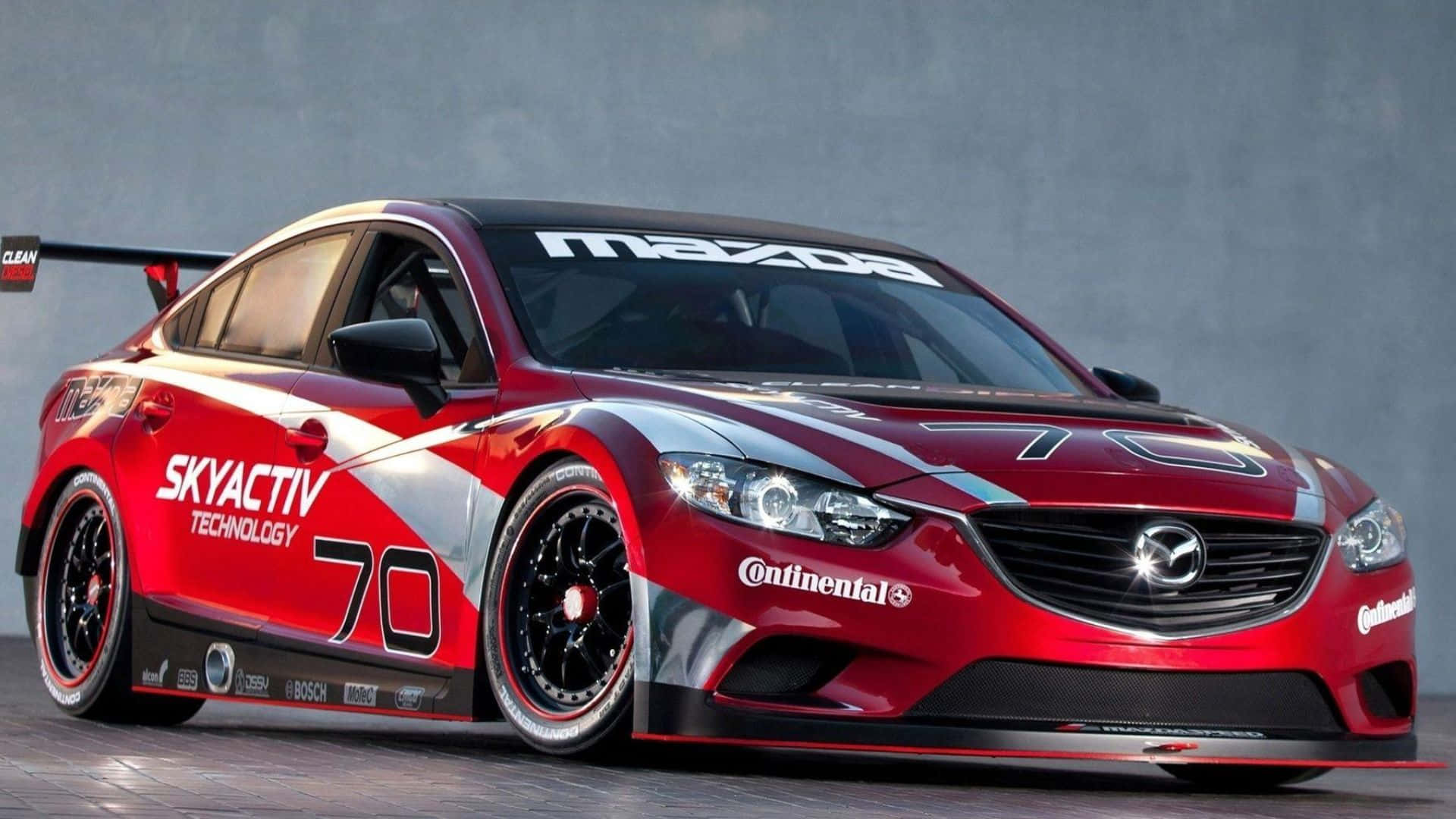 Mazda 6 桌布 壁紙 — 一輛帶有70號和SkyActiv品牌的時尚紅色Mazda賽車，在灰色工作室背景下蓄勢待發。