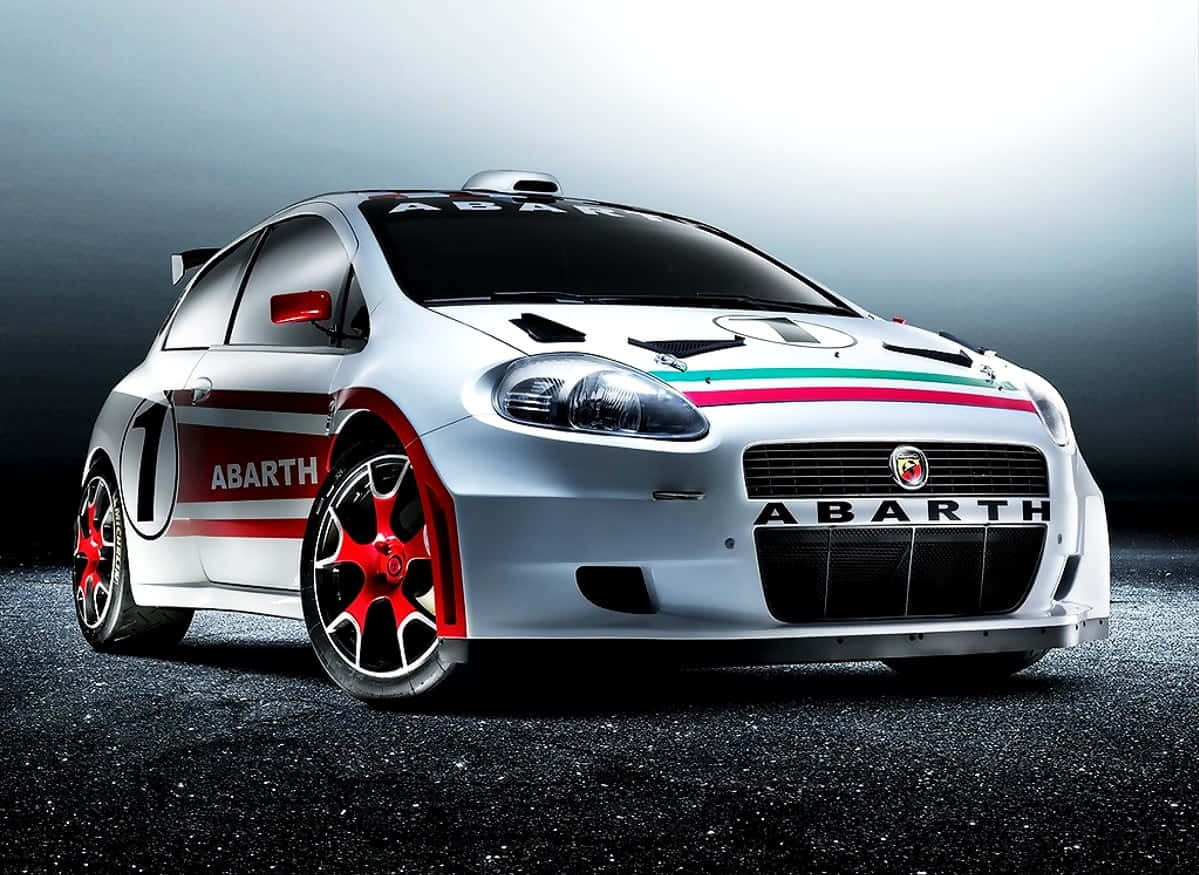 Fiat Punto 桌布 壁紙 — 一輛流線型的銀色 Abarth 拉力賽車，帶有紅色點綴和義大利三色條紋，在深色瀝青表面上於攝影棚燈光下閃閃發光。