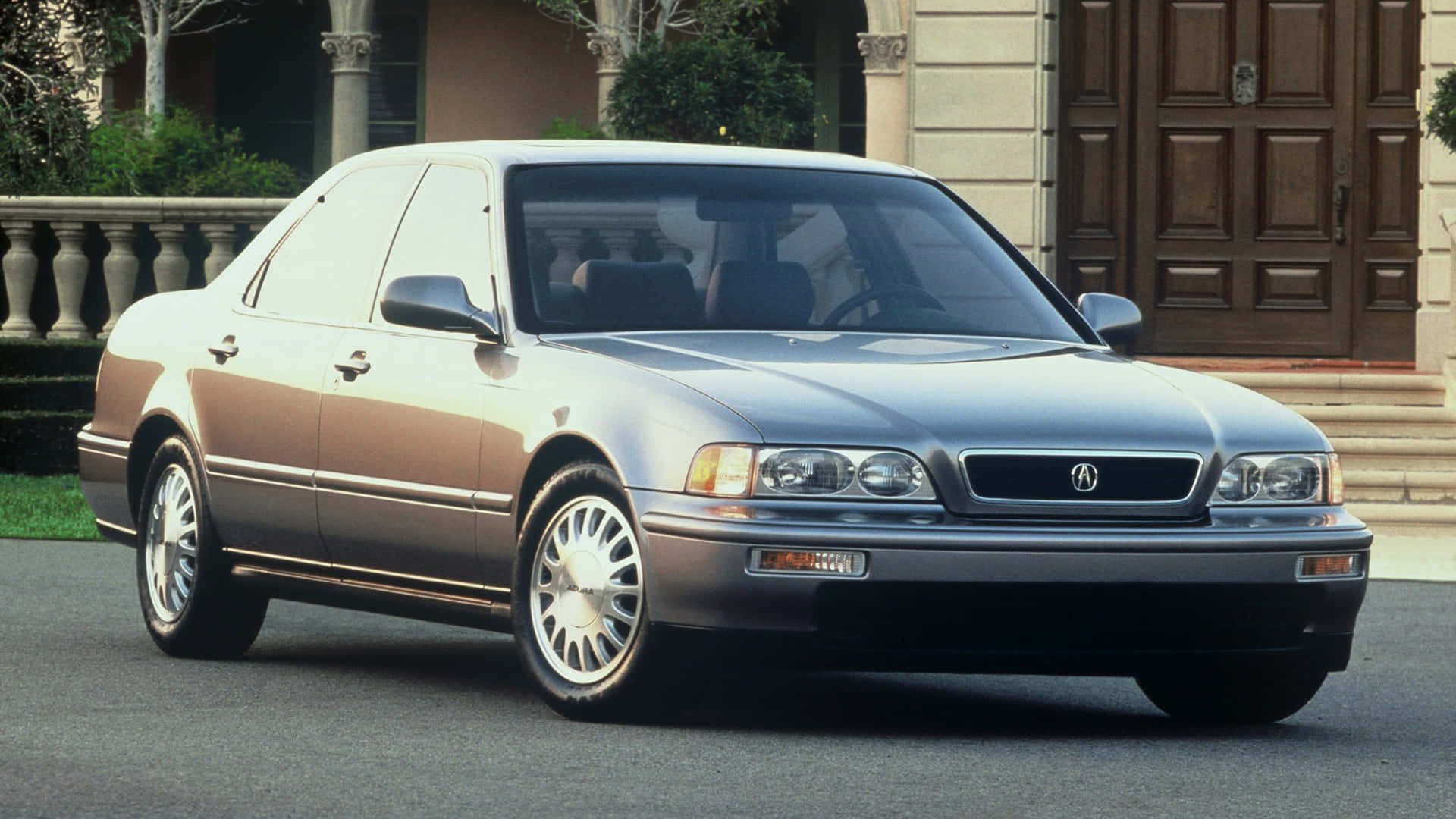 Acura Legend 桌布 壁紙 — 一輛時尚的銀色Acura轎車停放在一棟有木門和石柱的豪宅前的車道上。