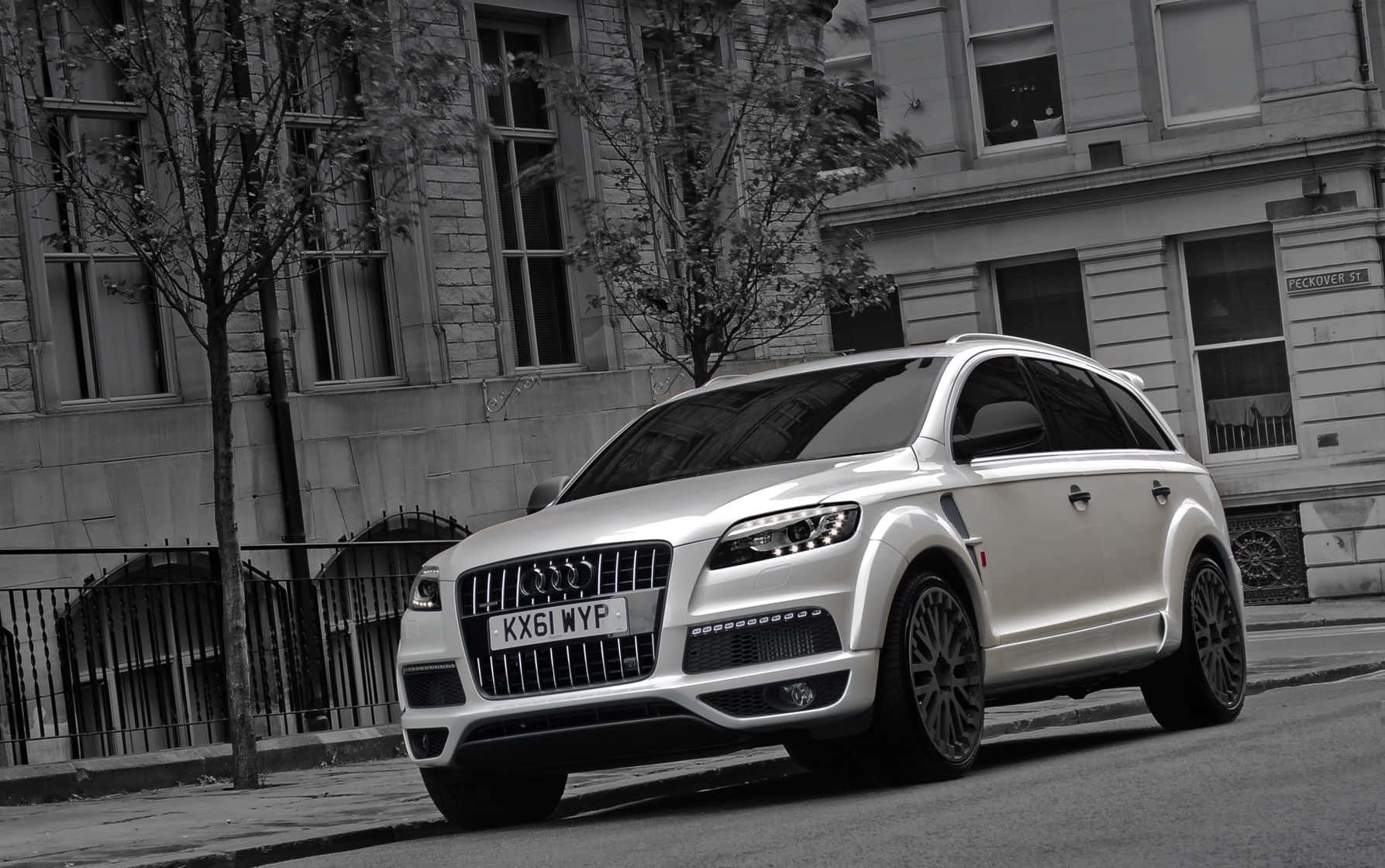 Audi Q7 桌布 壁紙 — 一輛時尚的銀色奧迪Q7運動型多功能車停在城市街道上，背景是歷史建築和光禿禿的樹木。