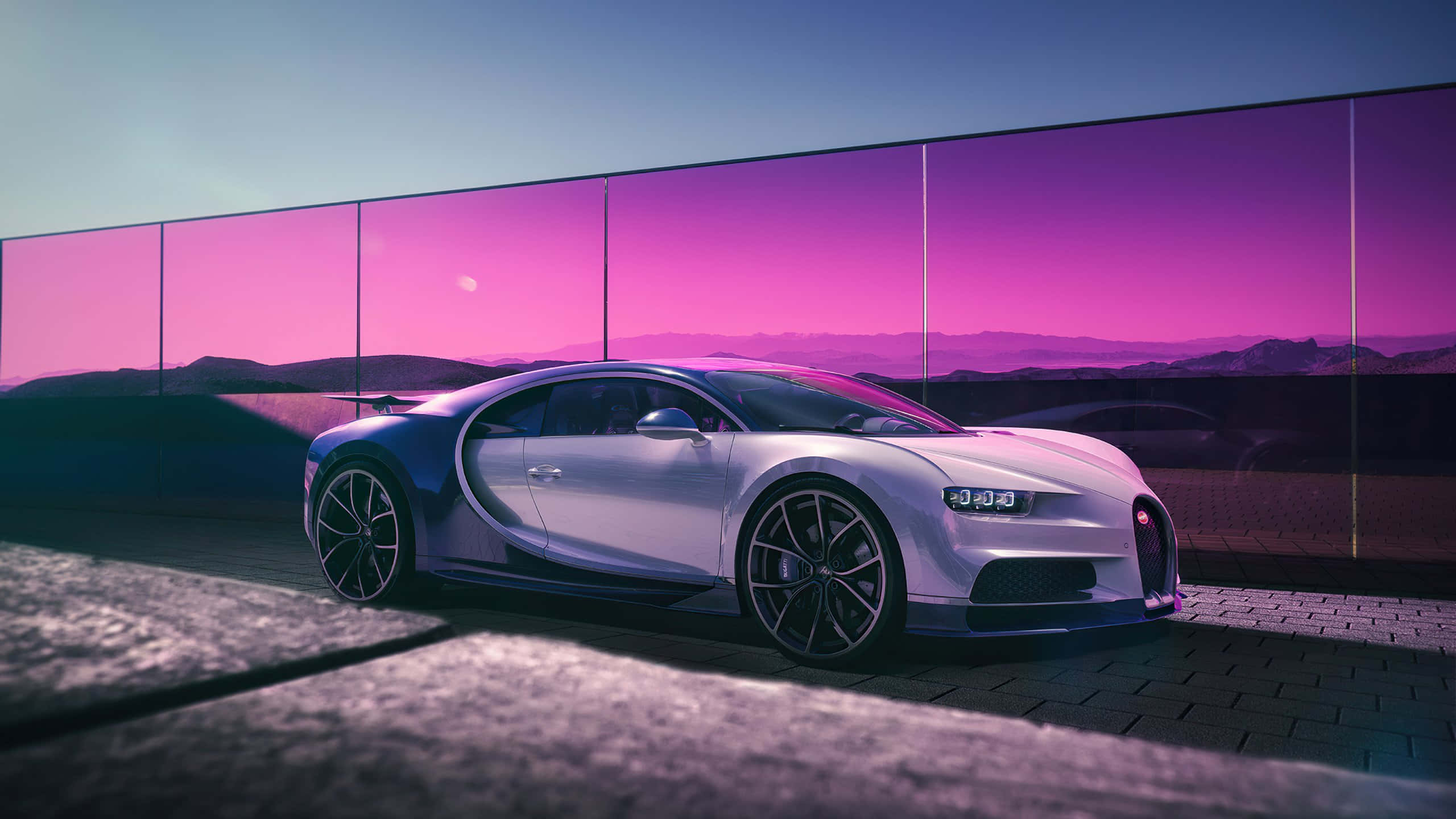 Bugatti Chiron 桌布 壁紙 — 一架流線型銀色Bugatti Chiron停放在鋪砌路面上，背後玻璃牆反射出鮮豔的紫色日落。