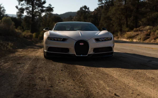日落時分，銀色Bugatti Chiron停泊在森林山區的泥土路上。 — 4K 壁紙