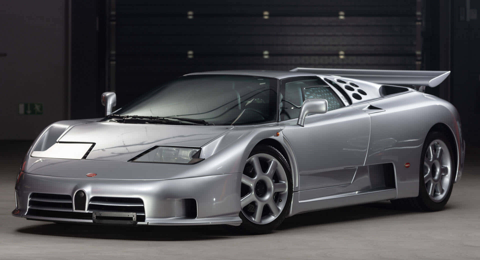 Bugatti Eb110 桌布 壁紙 — 一輛時尚的銀色布加迪 EB110 超級跑車在簡約車庫環境中的攝影棚燈光下閃閃發光。