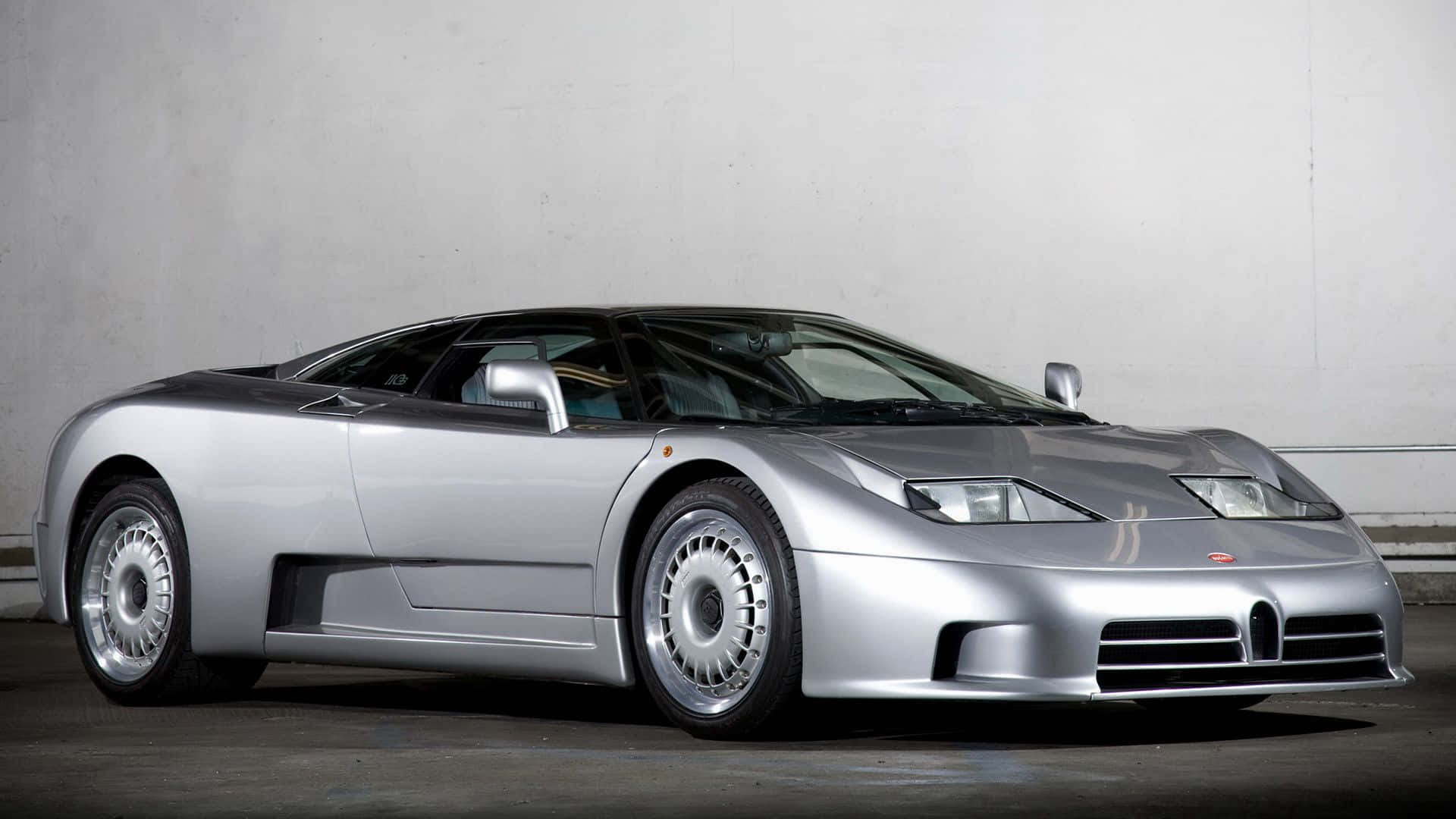 Bugatti Eb110 桌布 壁紙 — 一輛時尚的銀色布加迪EB110超級跑車在極簡混凝土背景下蓄勢待發，其空氣動力學曲線在柔和的工作室燈光下閃閃發光。