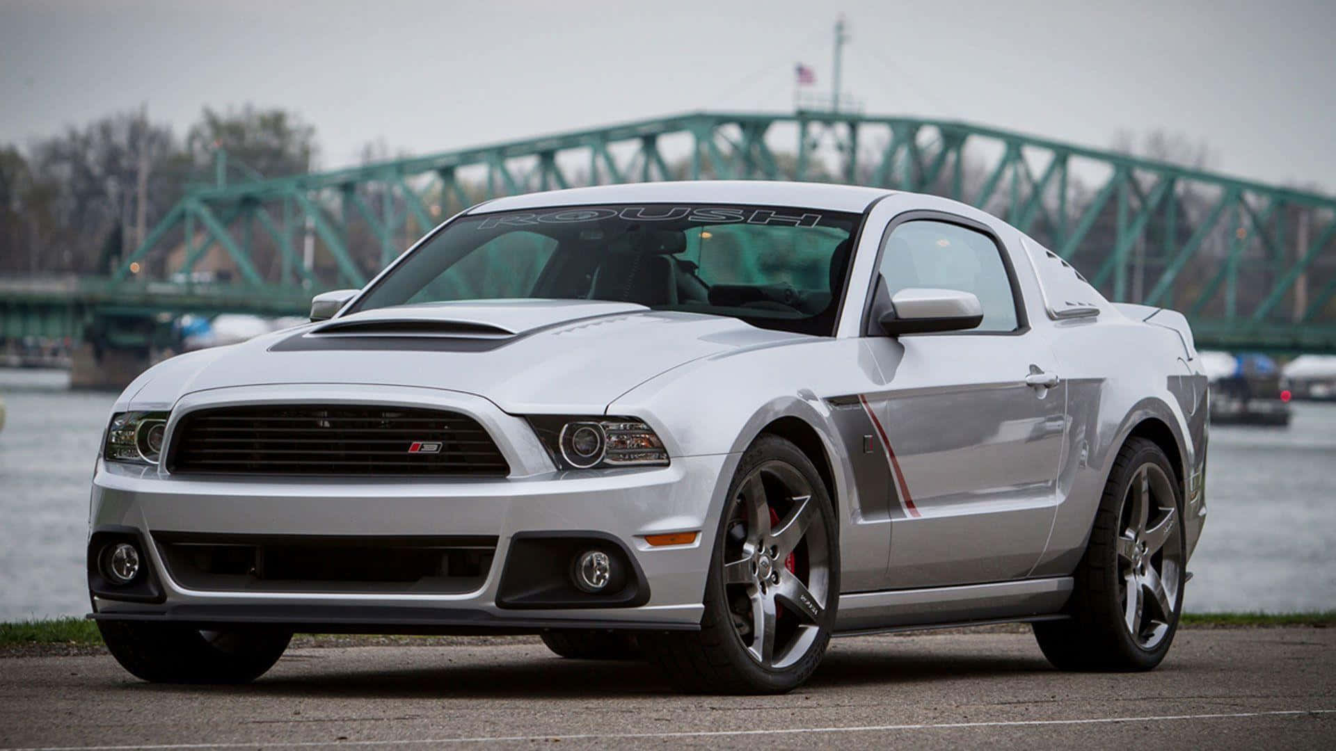 Ford Mustang Roush 桌布 壁紙 — 一架時尚的銀色福特野馬Shelby GT500停泊在河邊，背景有一座綠色桁架橋。