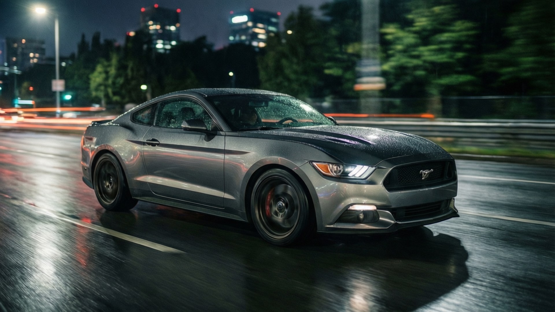 Grey Sports Car at Night 壁紙 — 一輛流線型的銀色福特野馬在雨濕的夜間城市街道上飛馳，模糊的燈光掠過。