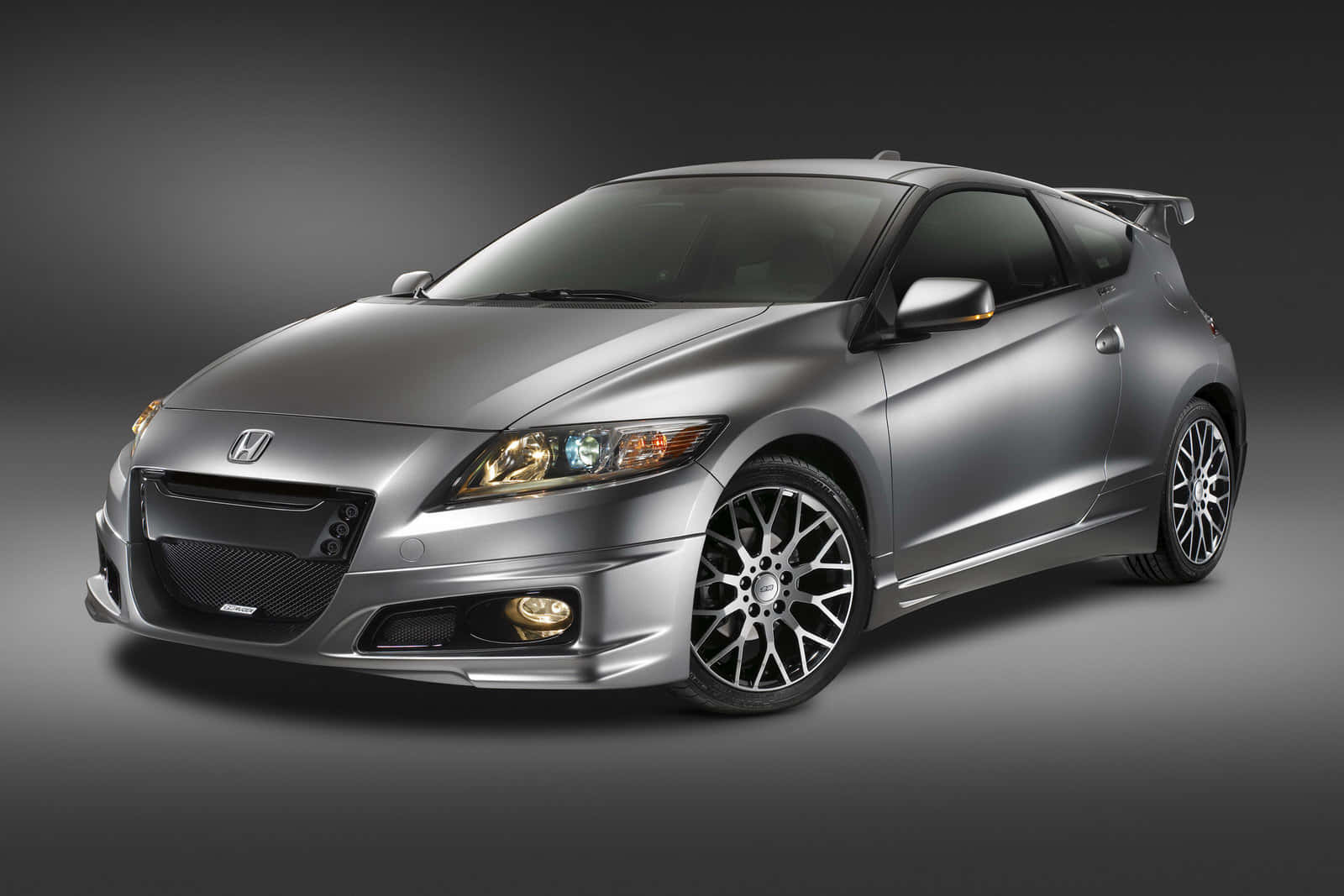 Honda Cr-z 桌布 壁紙 — 一部時尚的銀色本田CR-Z運動轎跑車，配備訂製輪圈和後擾流板，在深色攝影棚背景下展示。