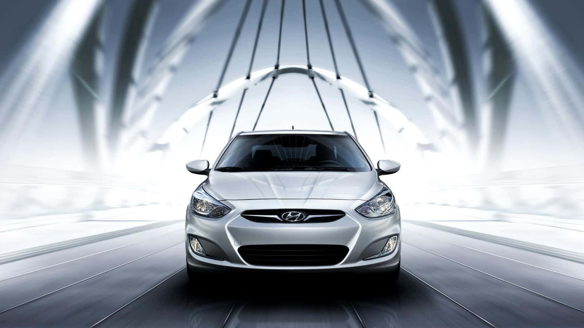 Hyundai Accent 桌布 壁紙 — 一輛時尚的銀色現代汽車在發光隧道下，於未來主義賽道上向前行駛，帶有動態光條。