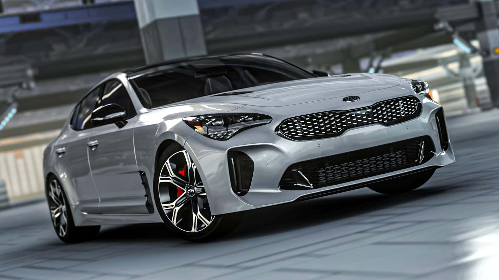 Kia Stinger 桌布 壁紙 — 一輛流線型銀色Kia Stinger跑車配備紅色制動卡鉗，在明亮的日光下沿著現代城市賽道飛馳。