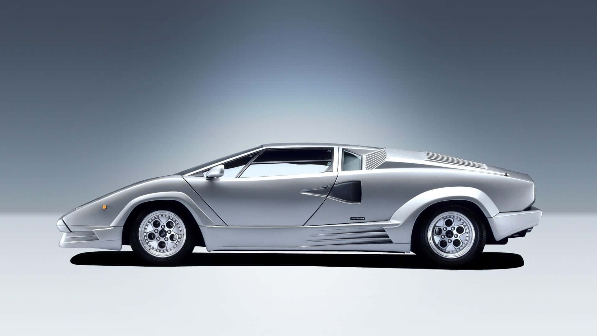 Lamborghini Countach 桌布 壁紙 — 一輛時尚的銀色藍寶堅尼Countach跑車在灰色漸變工作室背景中以側面展示。