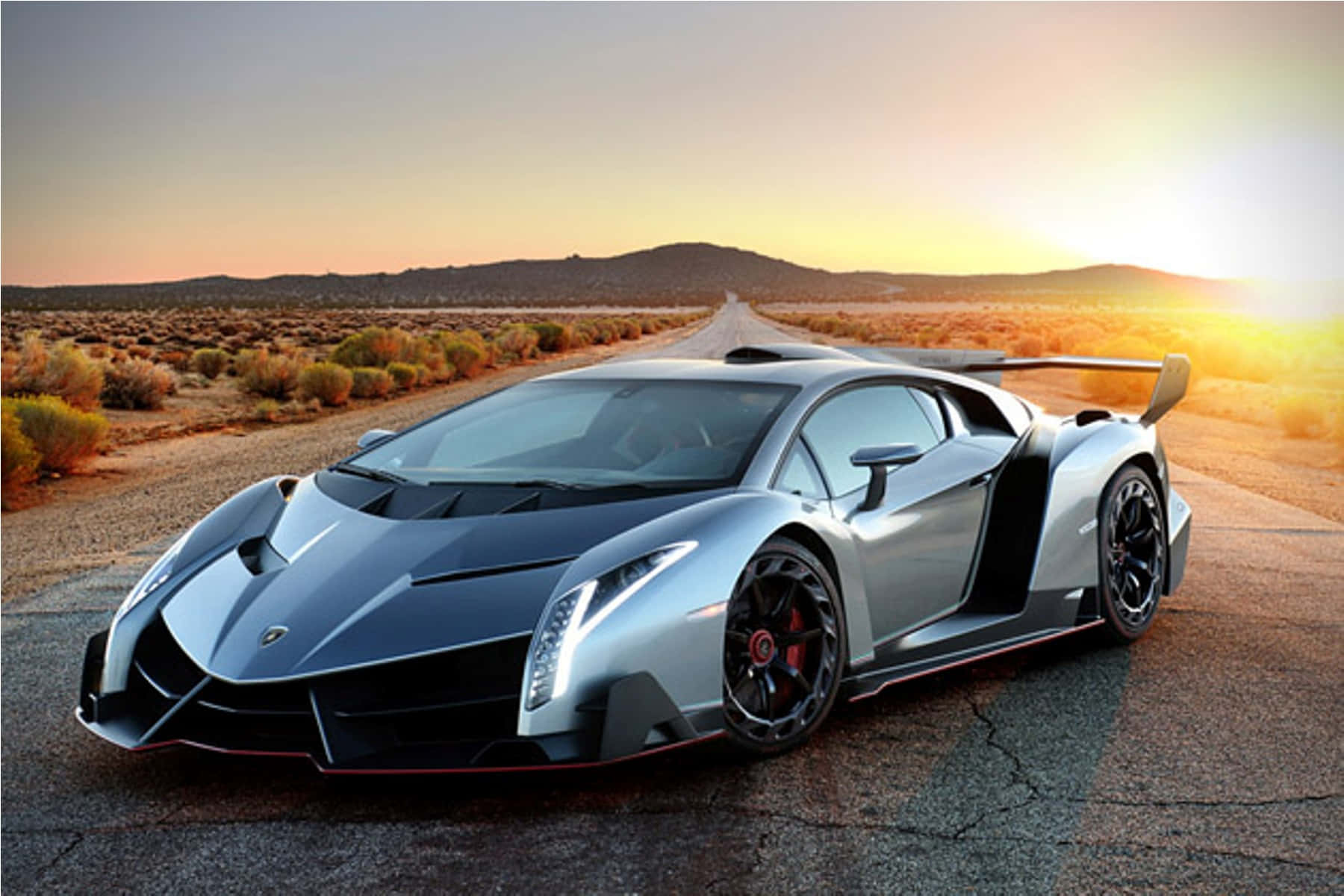 Lamborghini Veneno 桌布 壁紙 — 一架流線型銀色藍寶堅尼 Veneno 停在沙漠公路上，夕陽的金色光芒投下長長的影子。