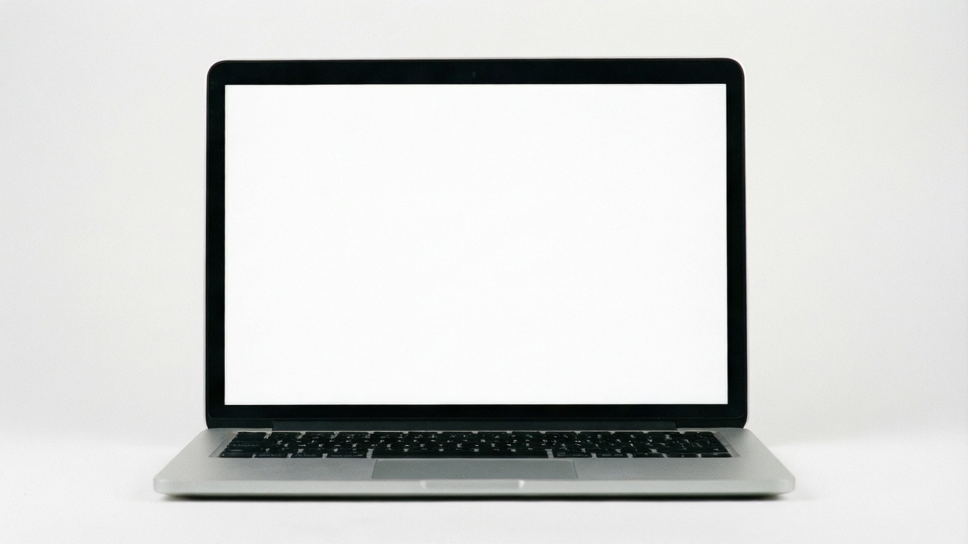 White Studio Laptop 壁紙 — 一部時尚的銀色筆記型電腦，配有黑色鍵盤和空白白色螢幕，居中放置在純白色表面上。