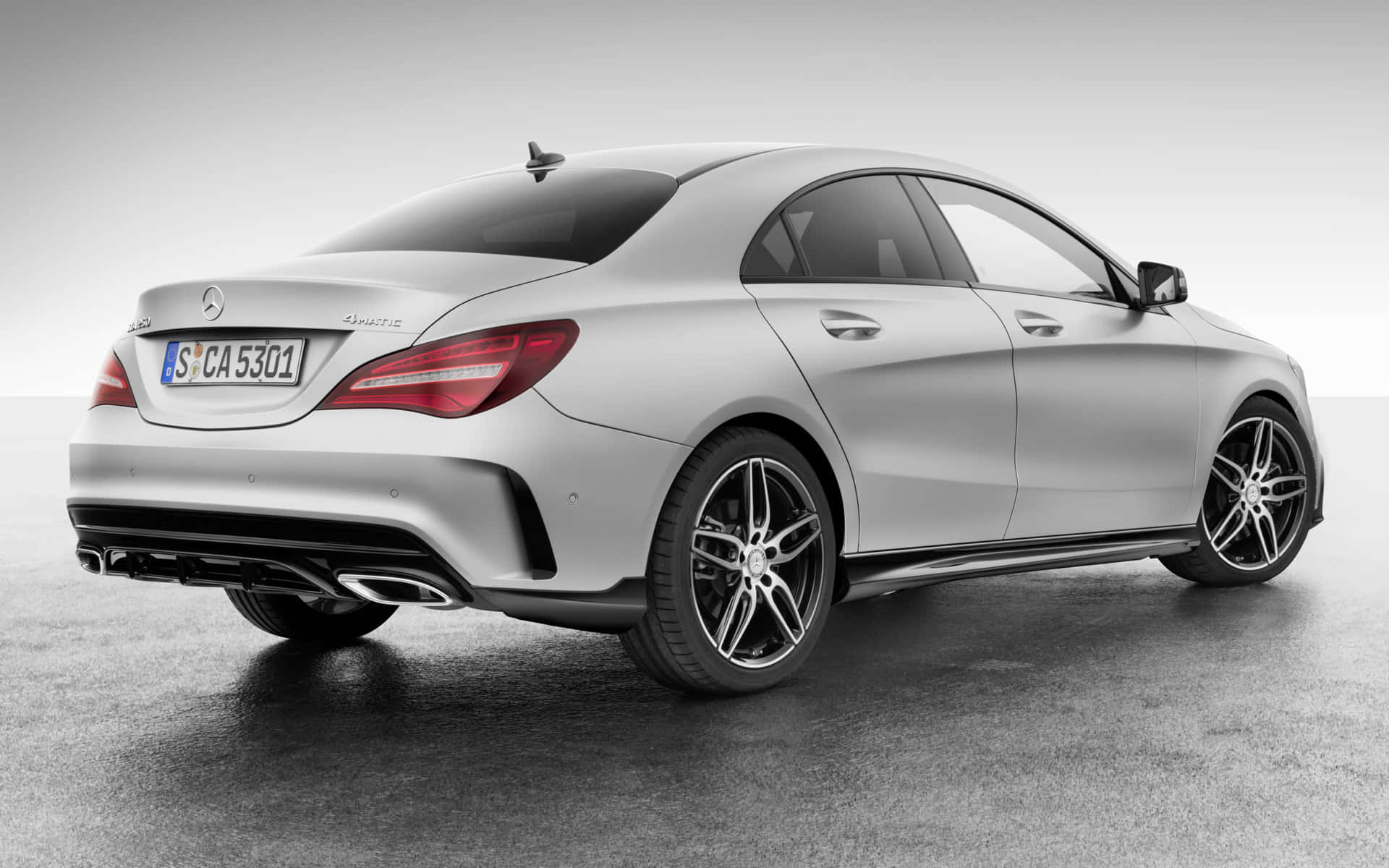 Mercedes Benz Cla-class 桌布 壁紙 — 一輛時尚的銀色Mercedes-Benz CLA 45 AMG轎車，以四分之三後視角度展示在簡約的攝影棚地板上，配以戲劇性的燈光。
