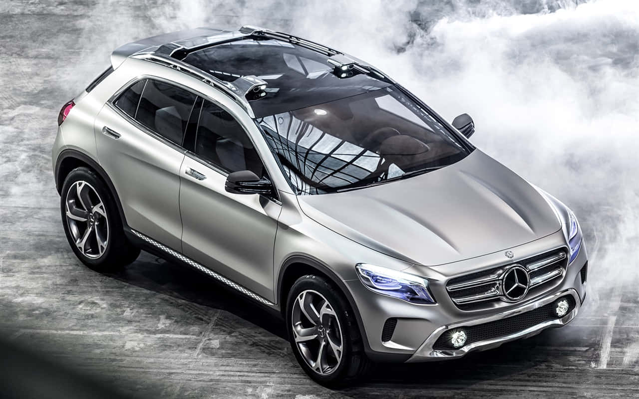 Mercedes Benz Gla-class 桌布 壁紙 — 一輛時尚的銀色Mercedes-Benz SUV，配備車頂行李架和發光頭燈，站立在混凝土地面上，周圍環繞著旋轉的煙霧。