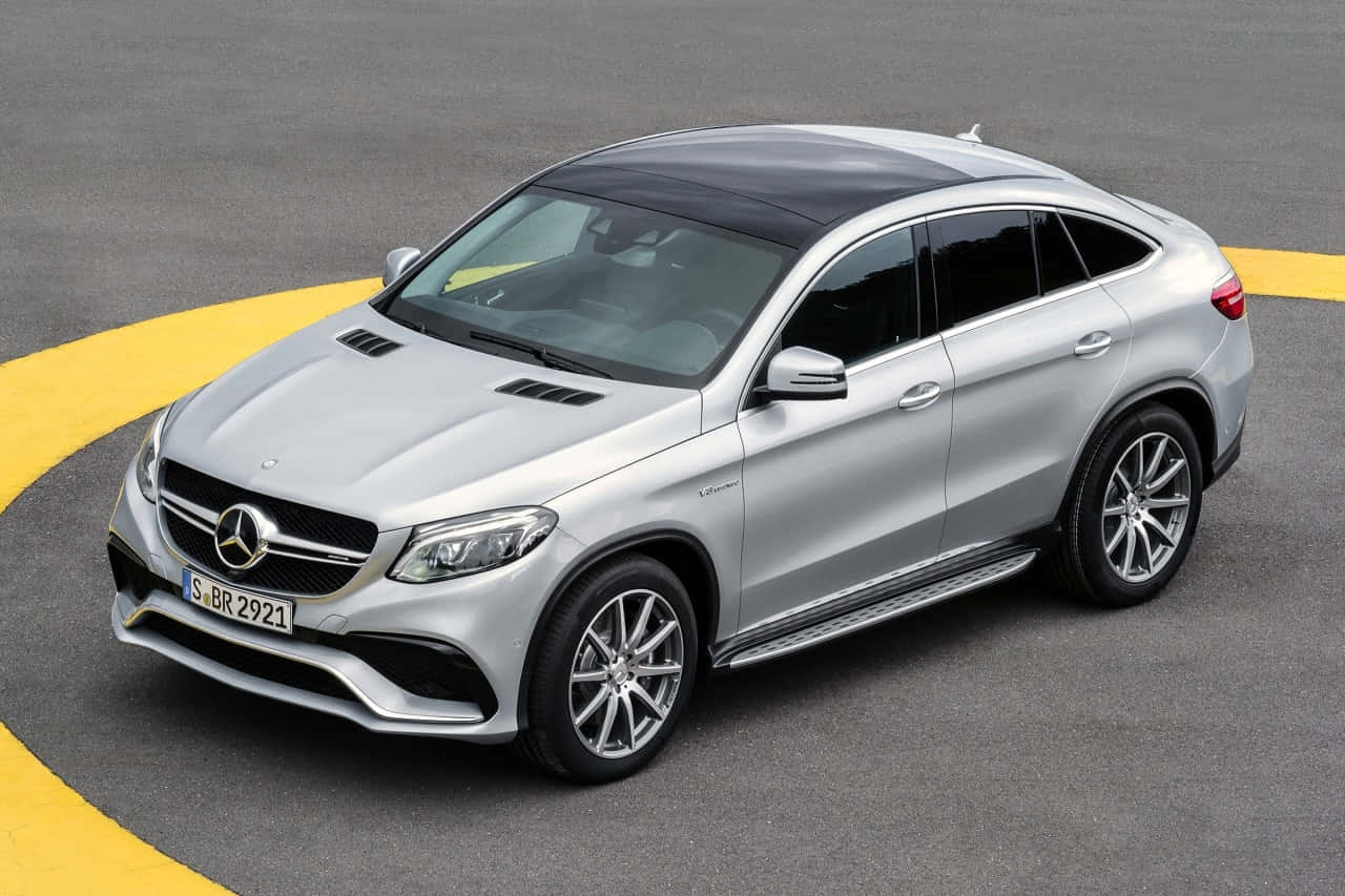 Mercedes Benz Gle-class 桌布 壁紙 — 一輛時尚的銀色 Mercedes GLE Coupe SUV 停放在灰色地面上，帶有醒目的黃色彎曲線條。