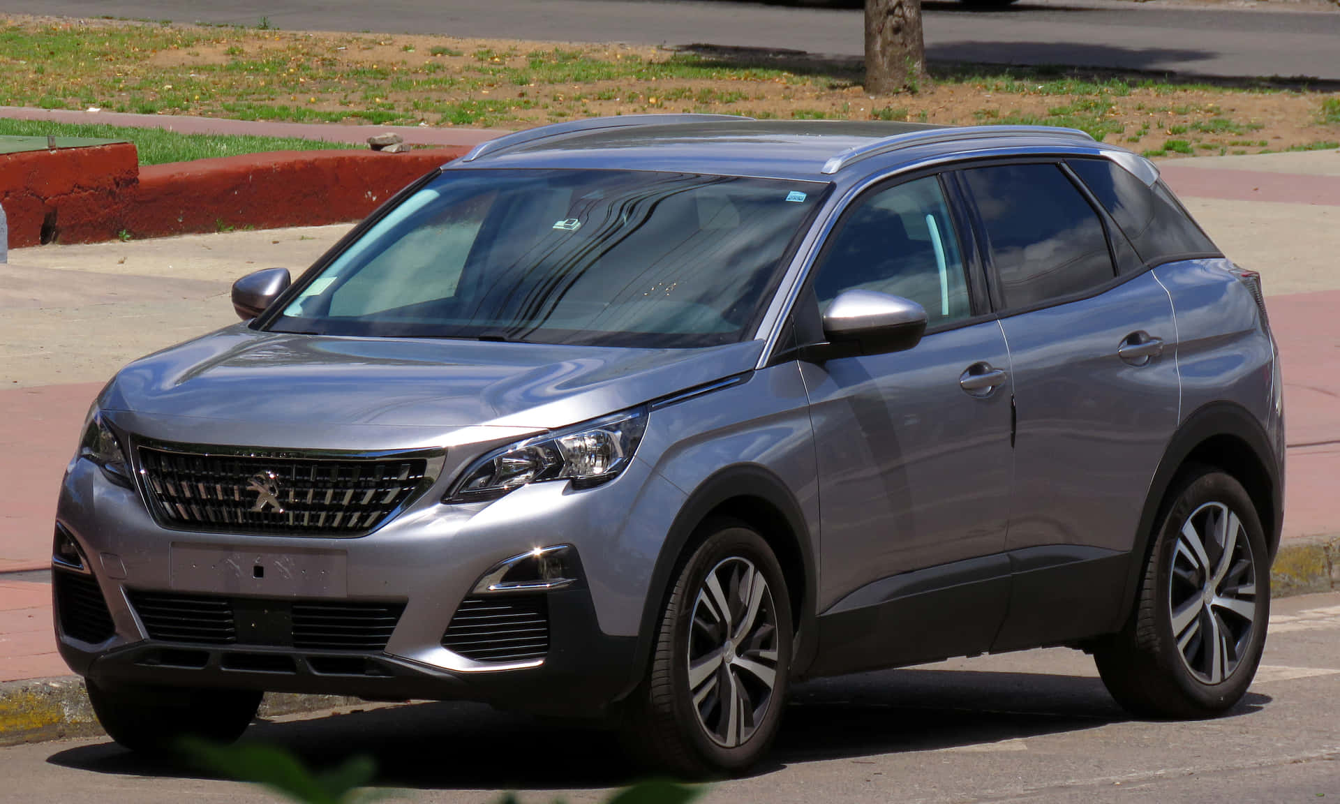  壁紙 — 一輛時尚的銀色Peugeot SUV停放在陽光普照的市區街道上，背景有綠化和人行道。