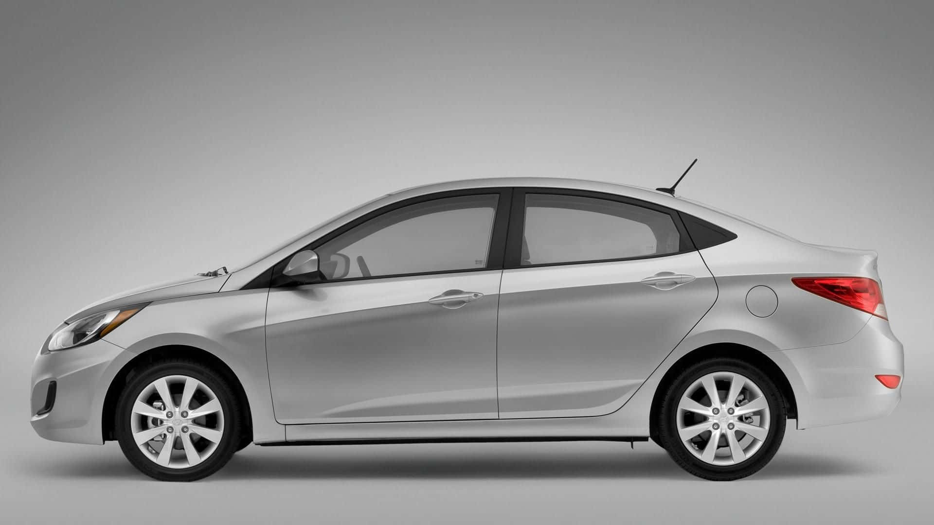 Hyundai Accent 桌布 壁紙 — 一輛時尚的銀色轎車在側面展示，背景為中性灰色工作室，光線柔和。