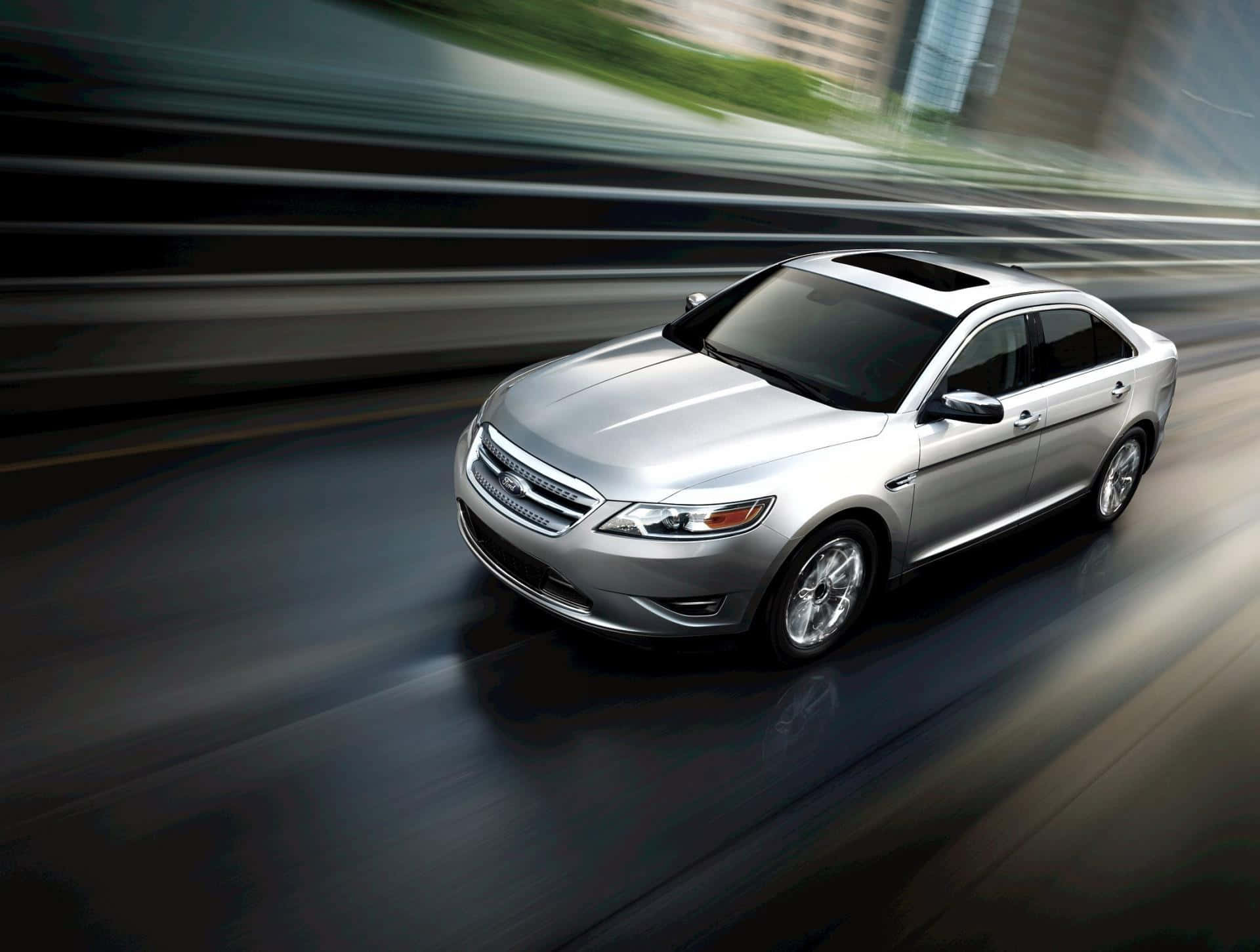 Ford Taurus 桌布 壁紙 — 一輛時尚的銀色轎車在模糊的城市高速公路上疾馳，動態模糊效果強調了速度。