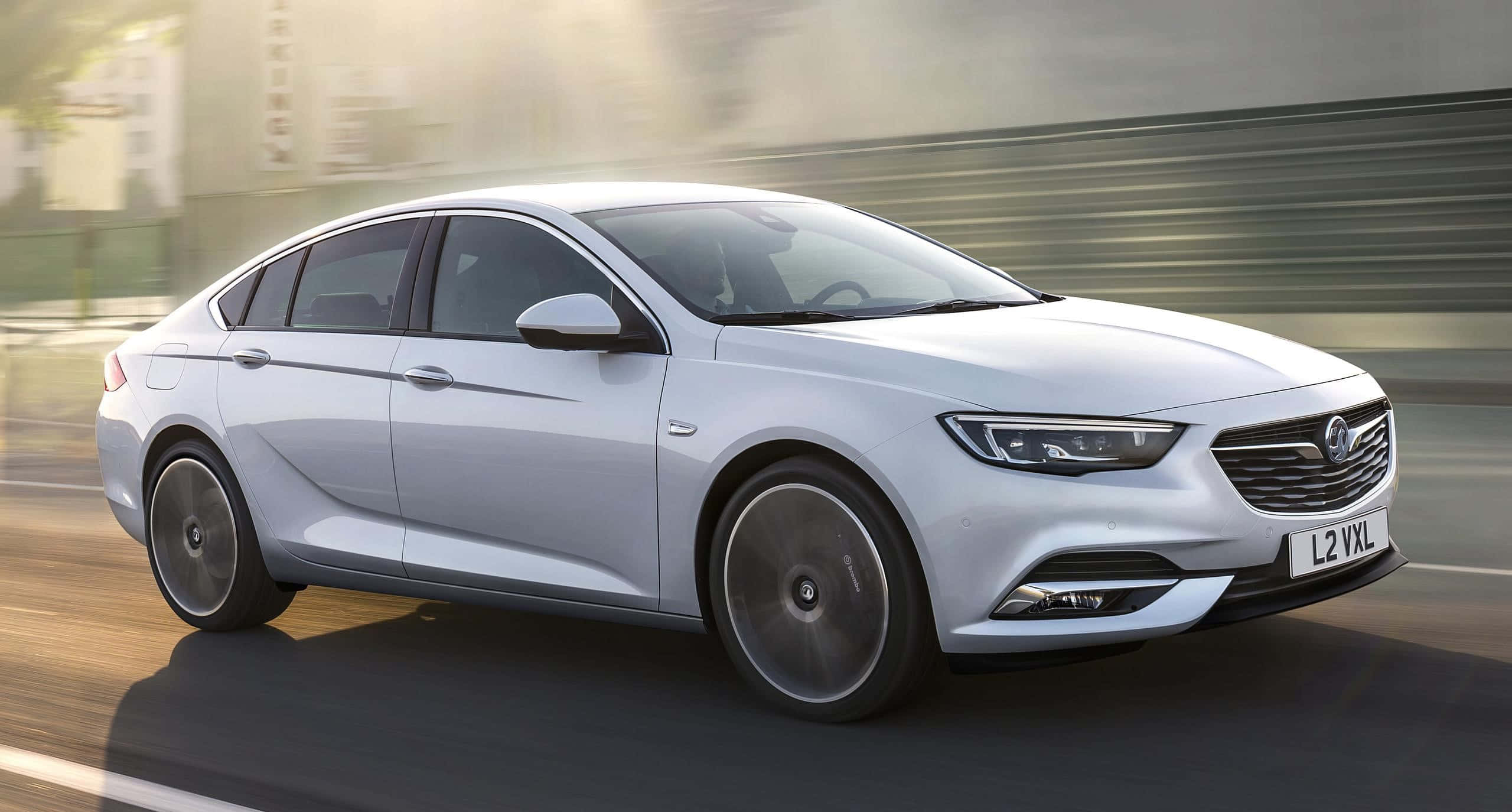 Opel Insignia 桌布 壁紙 — 一輛時尚的銀色轎車在模糊的城市道路上疾馳，動態模糊強調了其動態運動。