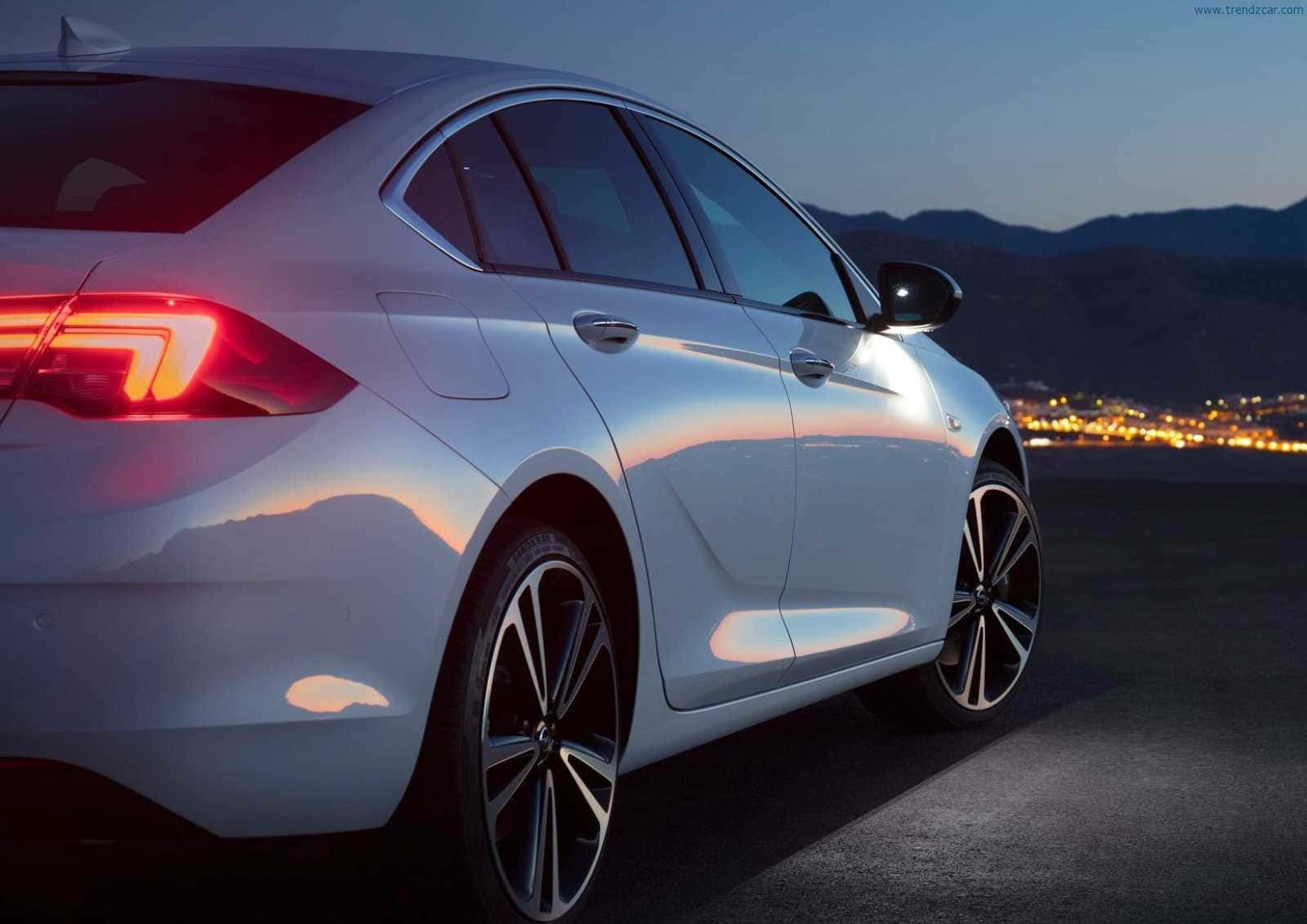Opel Insignia 桌布 壁紙 — 一輛時尚的銀色轎車在夕陽反射下閃耀，尾燈照亮了山巒暮色背景。