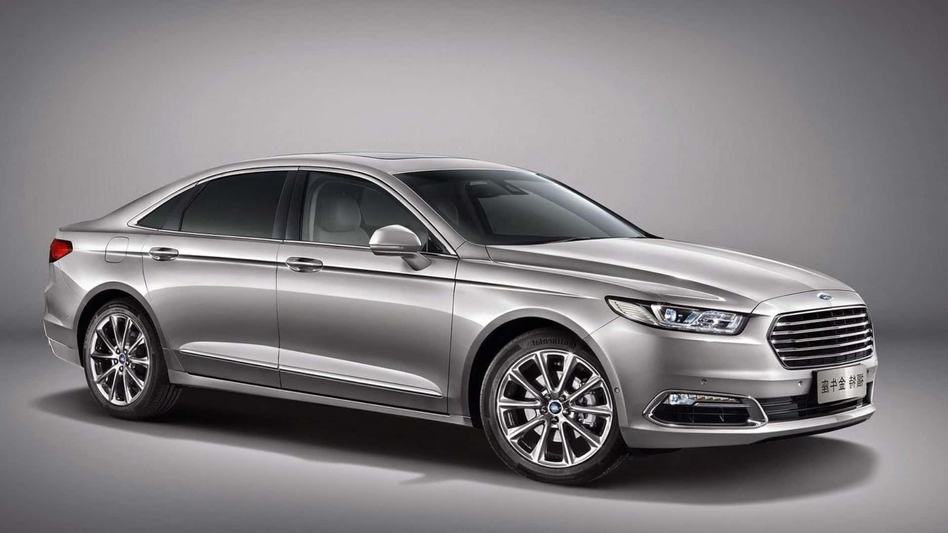 Ford Taurus 桌布 壁紙 — 一輛時尚的銀色轎車配備拋光合金輪圈，在簡約風格的攝影棚中展示，光線柔和。