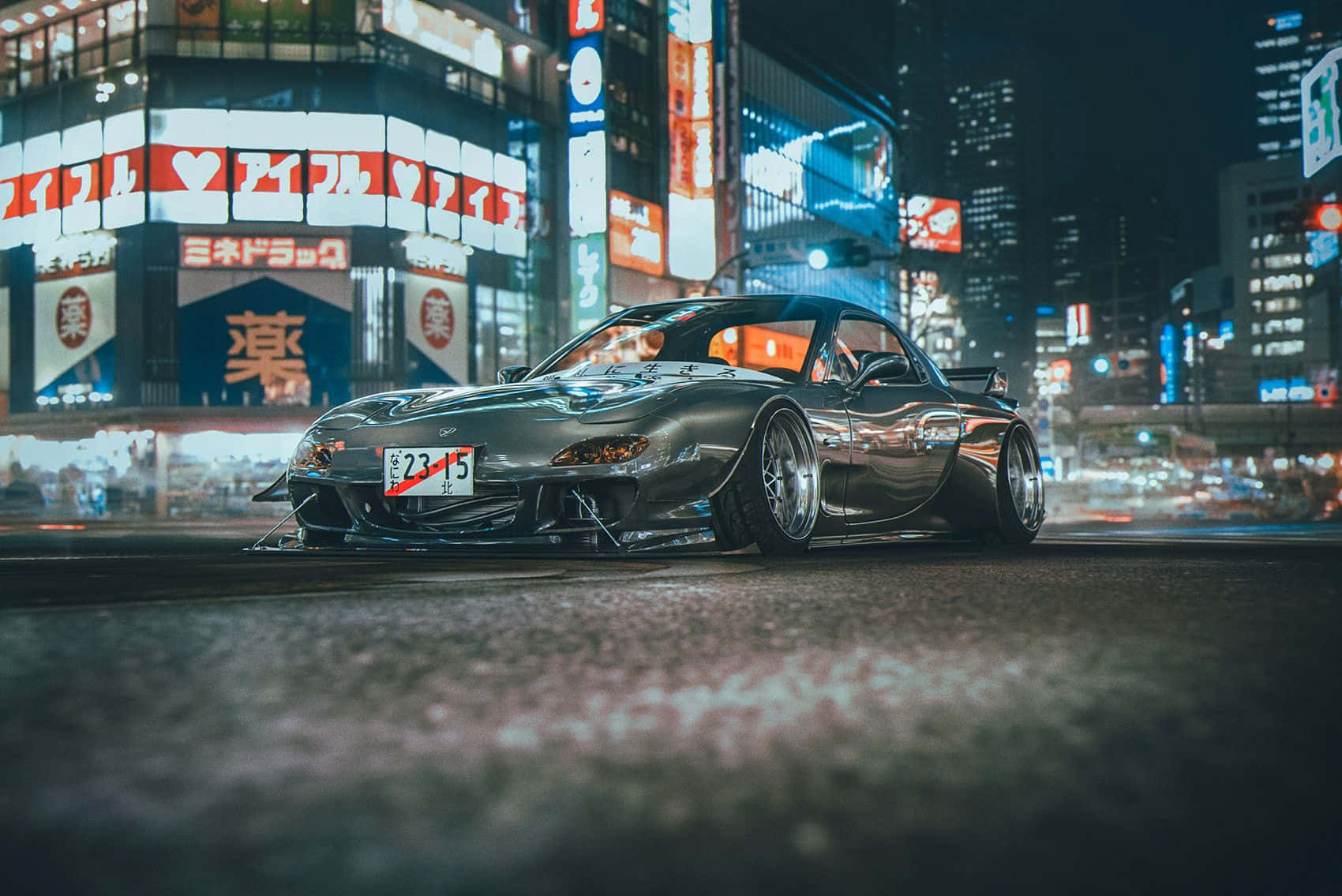  壁紙 — 一輛流線型銀色跑車在霓虹燈閃爍的東京街道上夜間行駛，背景是發光的招牌和模糊的城市燈光。